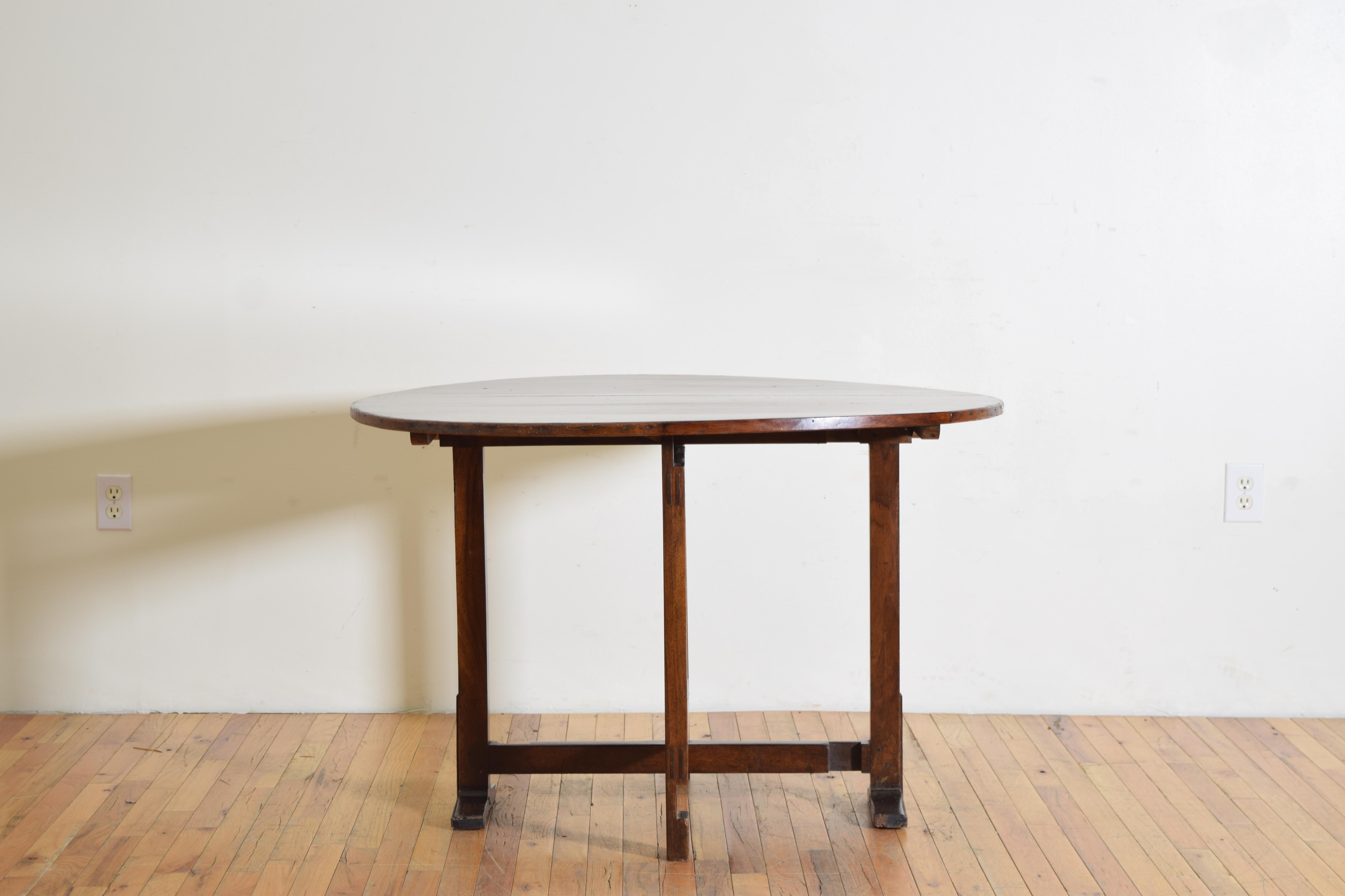 Having an oval top with a banded edge atop a trestle-form base with a pivoting center leg that locks into the main legs, the legs raised on bracket feet with iron braces