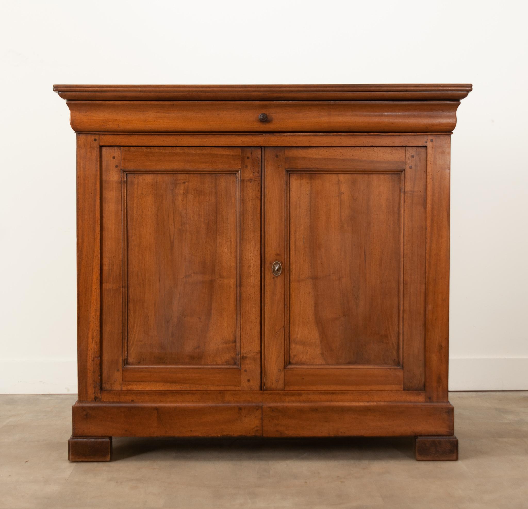 A charming solid walnut buffet hand-crafted in France at the beginning of the reign of Louis Philippe duc d’Orléans, circa 1830. A gorgeously patinated plank top with a molded edge sits over a long shaped frieze drawer with a trimmed wooden pull and