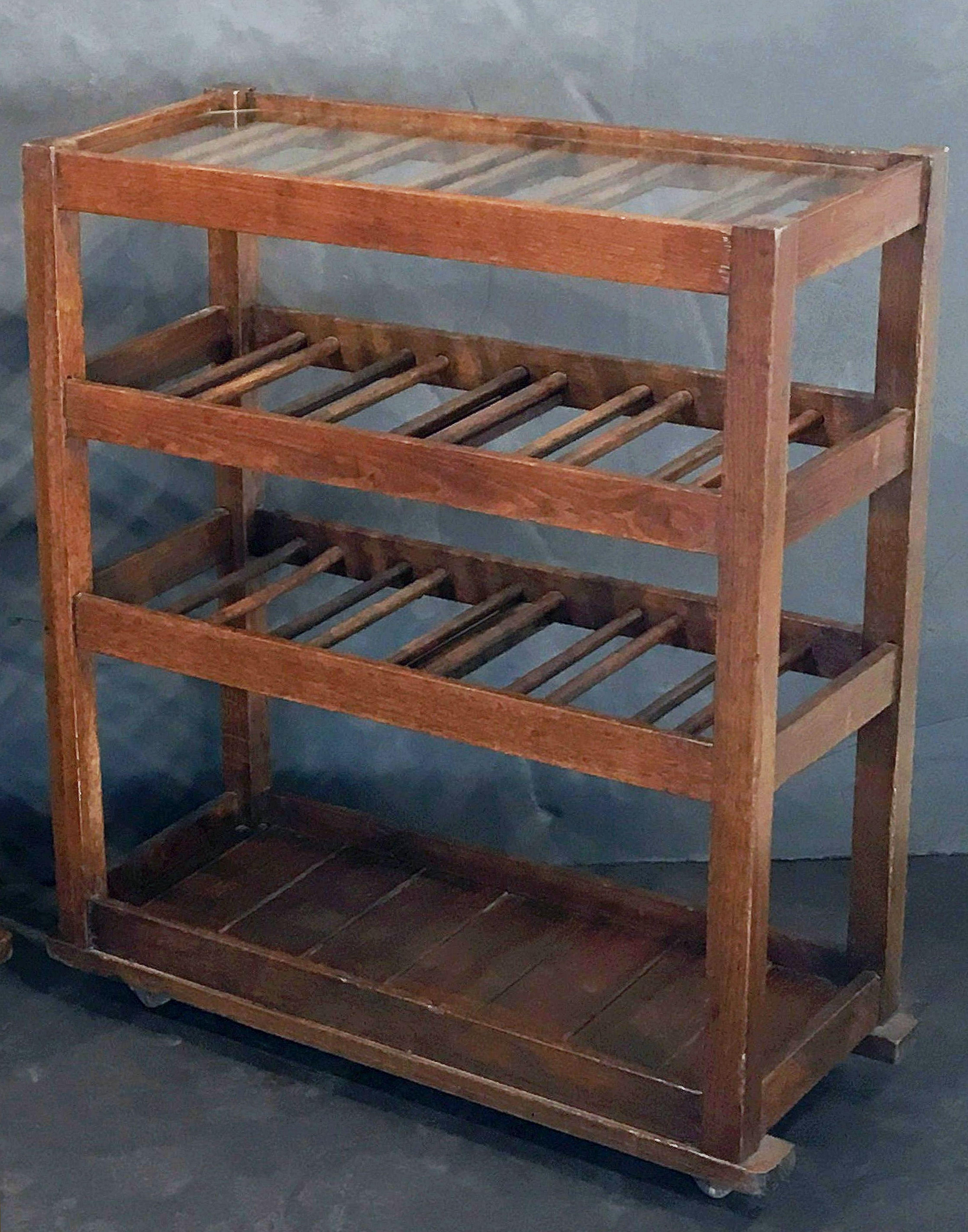 A fine French sommelier or wine tasting table, featuring a removable fitted glass top, upon a frame with two slatted shelves, designed for the presentation of bottles of wine, over a bottom shelf, and set upon four casters.

Note: The casters are