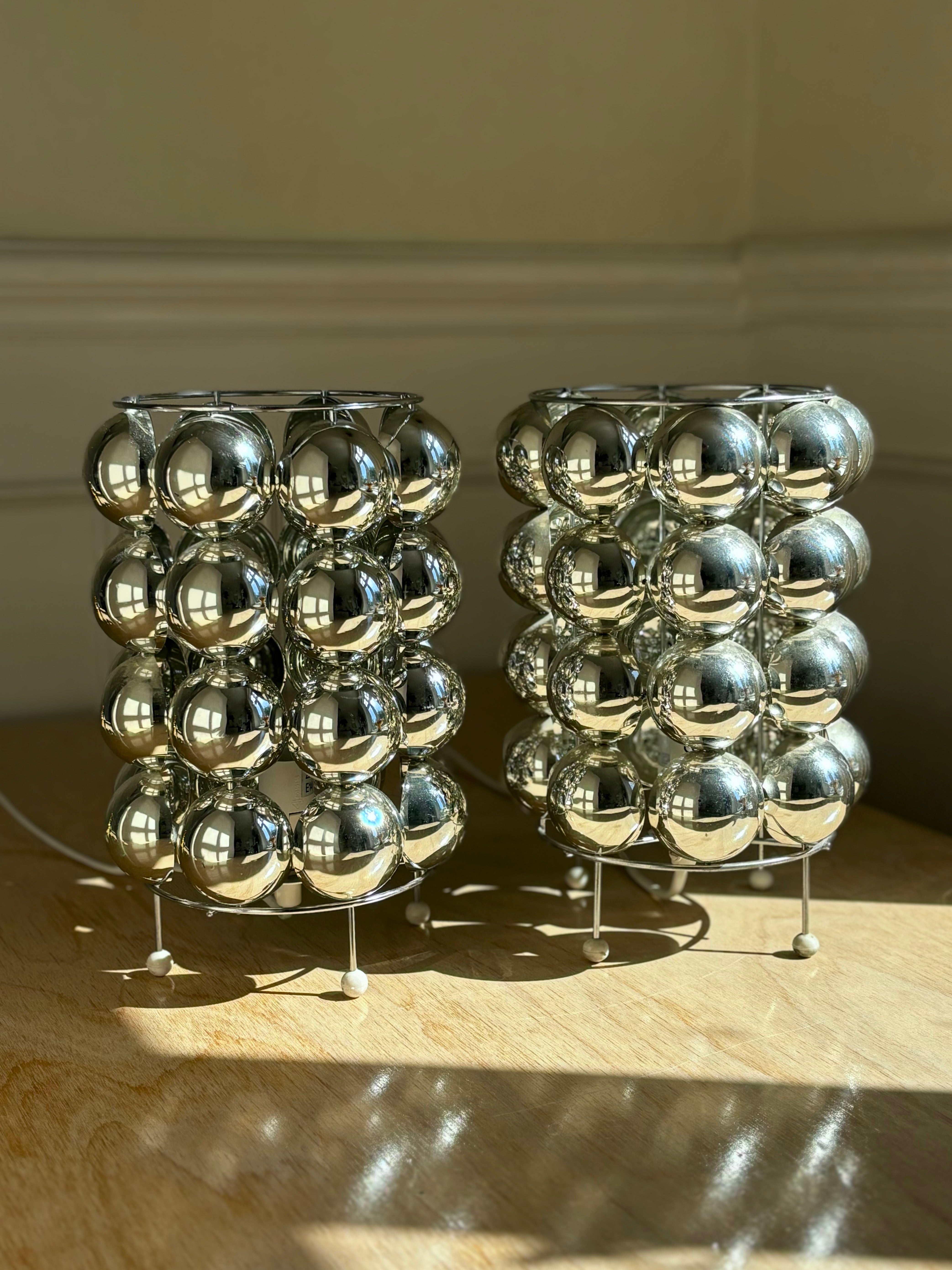 Pair of two French Atomic Age bubble shaped table lamps from the 1970s-1980s. Acrylic shiny silver colored semi-circles with mirror effect on metal mount with round white feet. One lamp with small damage on back - see photo. Wiring for EU and US