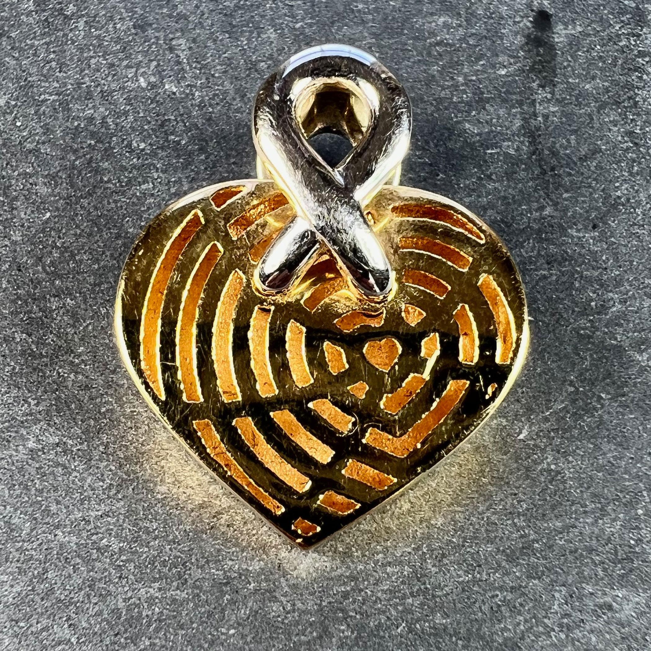 A French 18 karat (18K) yellow gold pendant designed as a three-dimensional love heart, the front of which is pierced to represent a spider's web of radiating hearts. The pendant bail is a white gold twist attached to both sides. Stamped with the