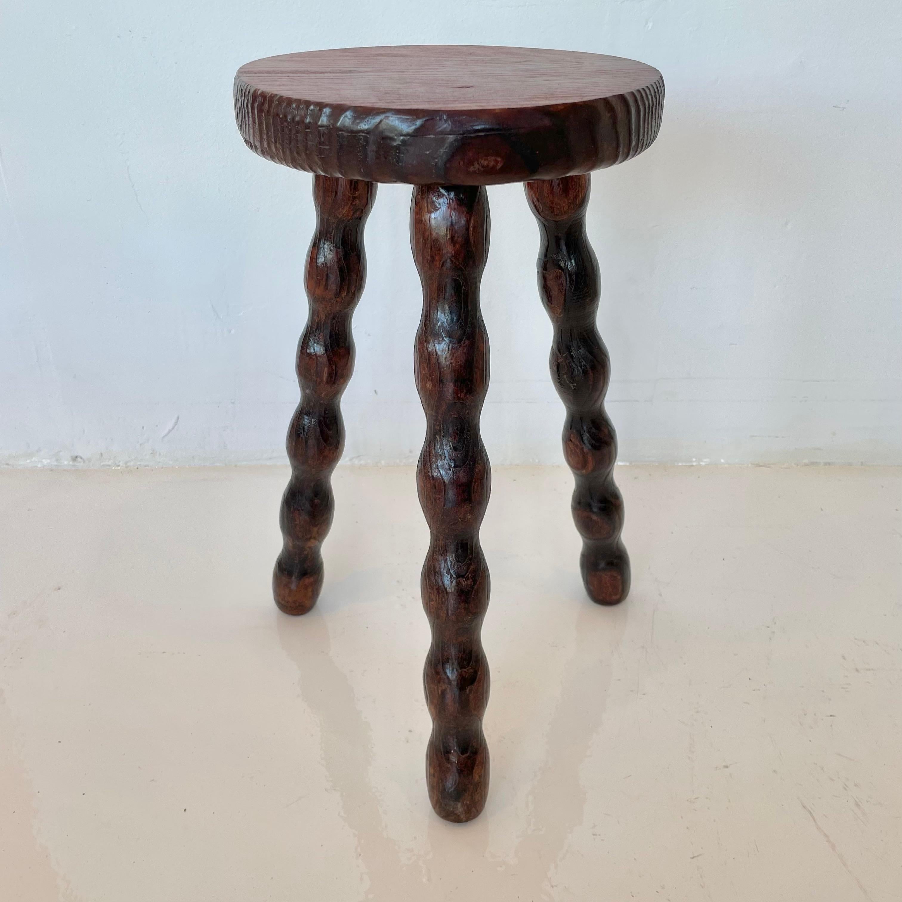 Fantastic wood stool from France made in the 1960s with three spiral legs. Beautiful wood grain and texture as well as a deep burgundy color to wood. The initials MD engraved on the bottom. Good vintage condition.
       