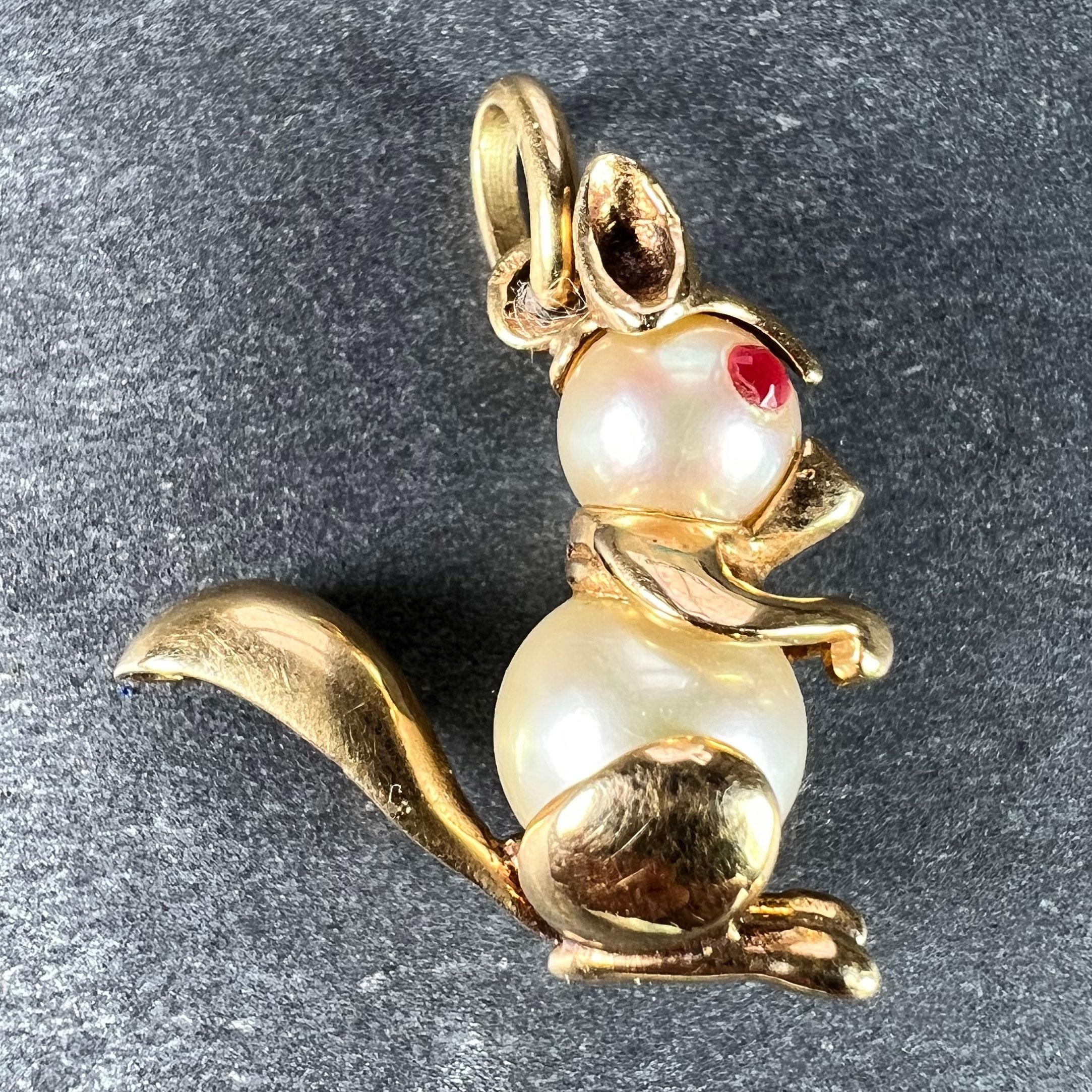 A French 18 karat (18K) yellow gold charm pendant designed as a squirrel with a body made of two cultured pearls measuring 0.68cm and 0.54cm in diameter, with red paste eyes. Stamped with the eagle's head mark for 18 karat gold and French