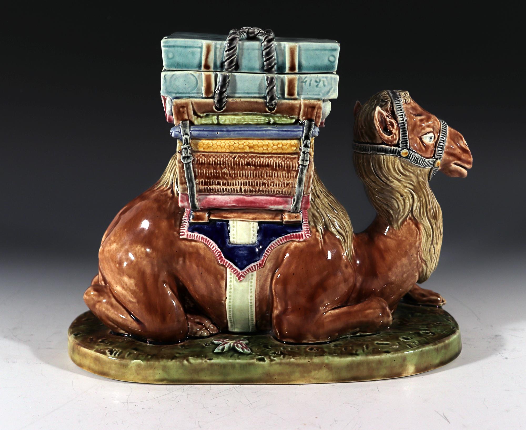 French Majolica Camel-form Lidded Box,
St. Amand,
circa 1870

The French majolica box is in the form of a seated, naturalistically colored, camel on a raised mottled green ground. On its back is a loaded pack filled with different packed goods.