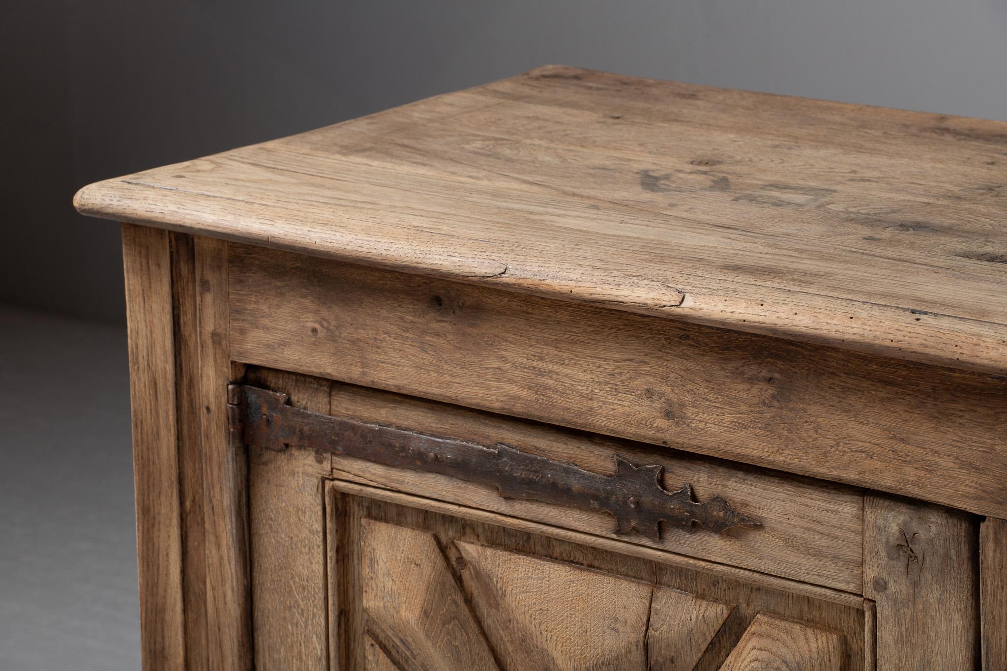 Standing as a quiet monument to rural French artistry of the late 19th century, this oak buffet conjures a poetic tension between architectural rigor and decorative modesty. With its crisply carved starburst panels and time-softened patina, the