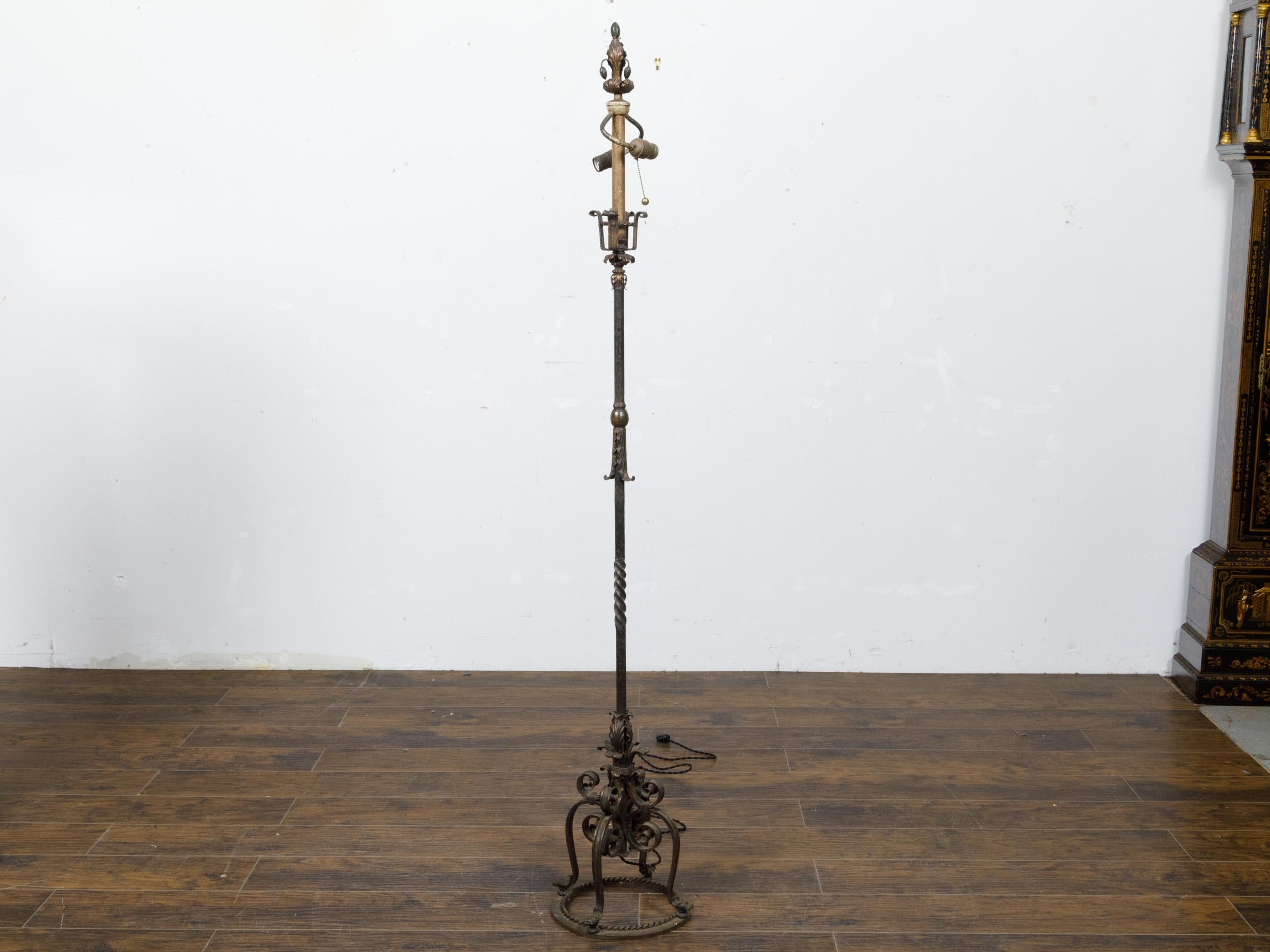 A French steel and brass floor lamp from circa 1930 with two light sockets, scrolling legs and foliage motifs. This French steel and brass floor lamp from circa 1930 is a testament to the elegance of early 20th-century design. Standing on a trio of