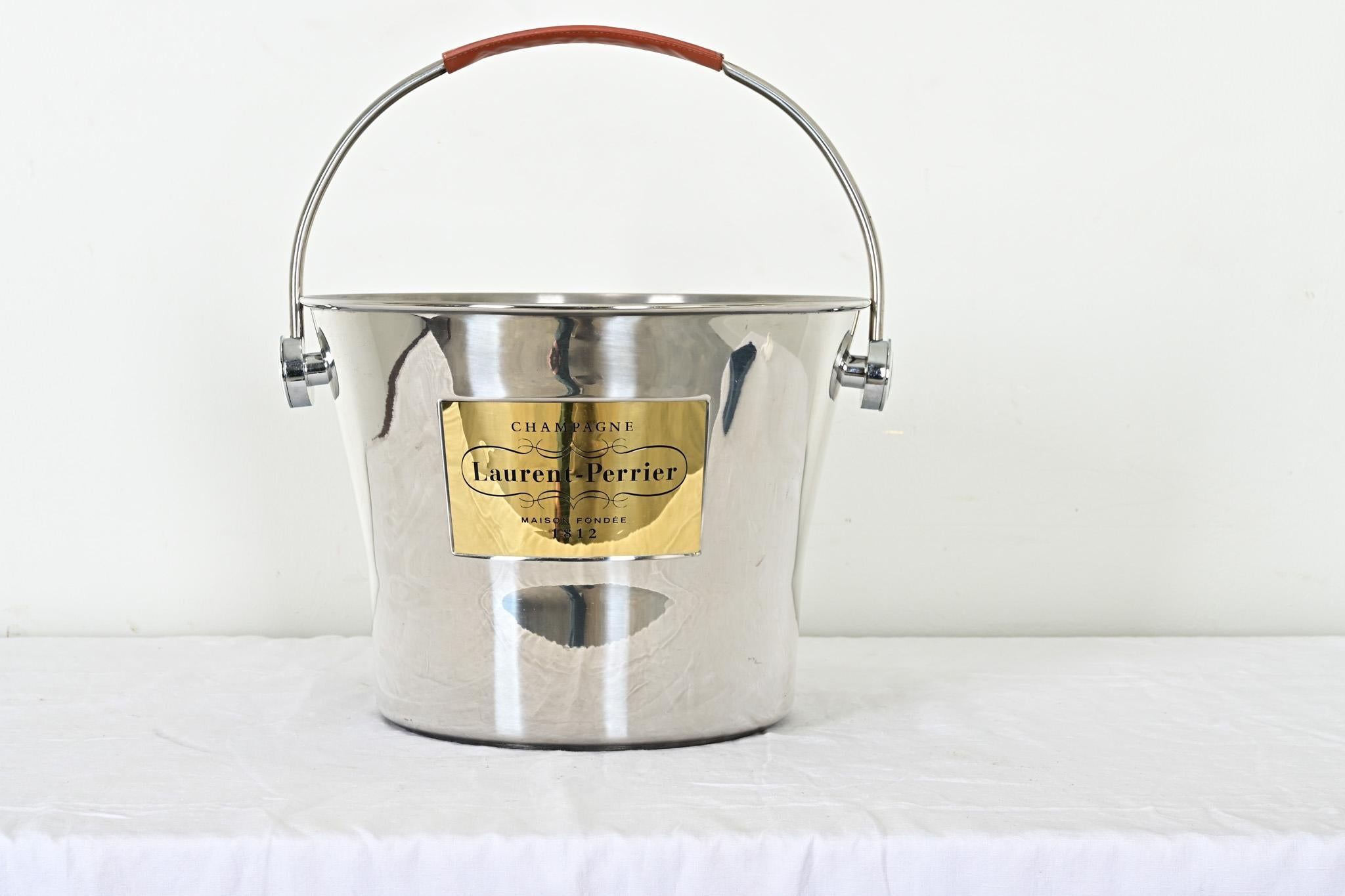 Irgendwo zwischen einem Korb und einem Eimer liegt dieser riesige Champagnerkühler aus Edelstahl mit Messingetikett des renommierten französischen Herstellers Laurent Perrier. Der große, abnehmbare Griff bietet einen durchdachten Lederriemen für