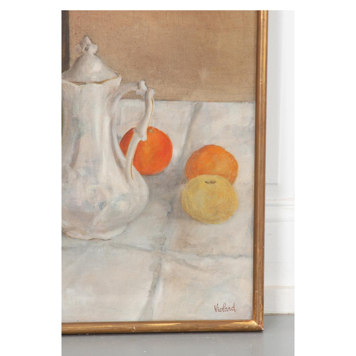 This is a delightful still life oil on canvas painting depicts a French kitchen. A glass storage jar, white sugar and cream containers, and fruit sit easily on the white tile counter. The slim gold gilt frame has a charming patina that pairs nicely