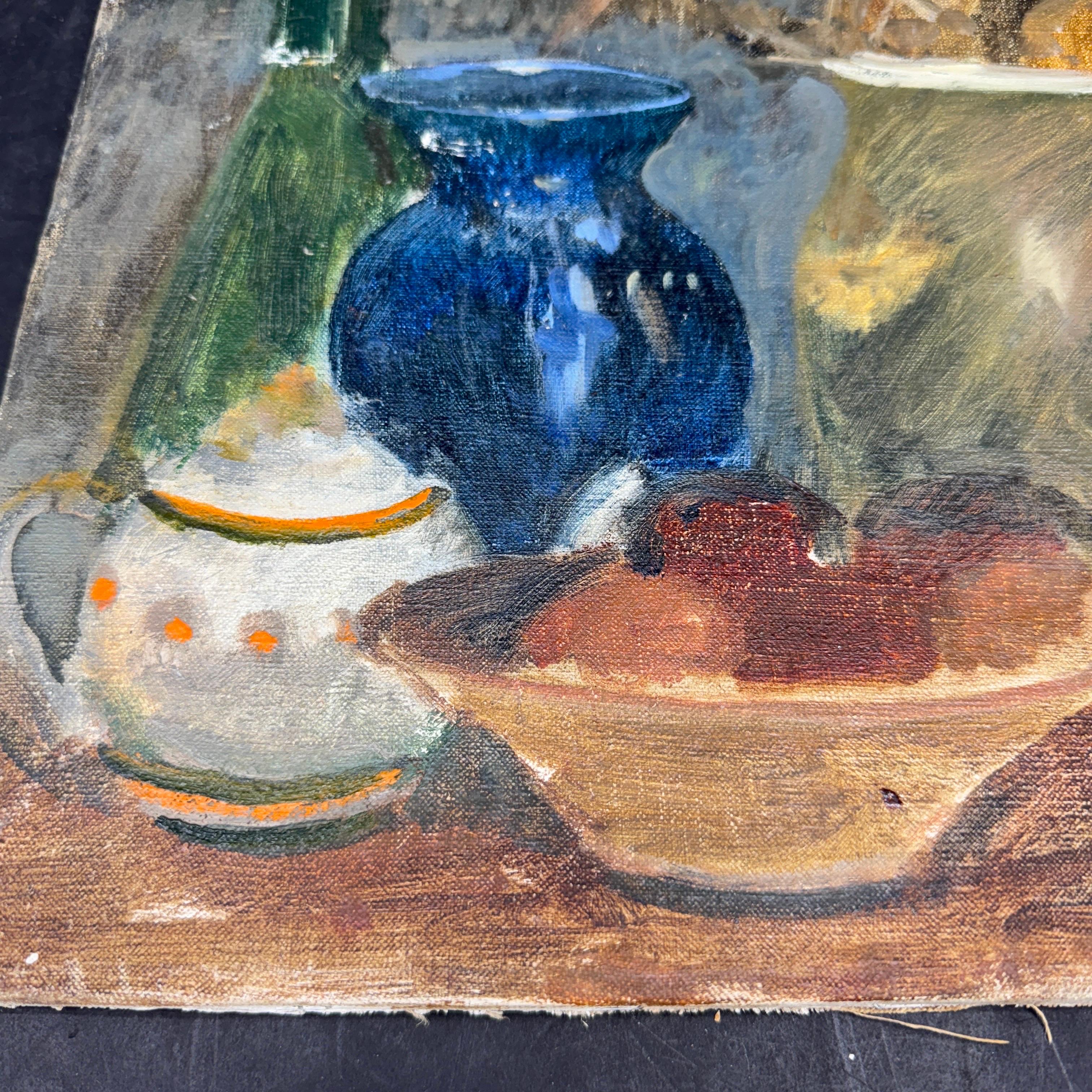 Still life oil painting on canvas with very lifelike table scene of a European countryside kitchen or workstation. This 20th Century still life painting features a tian bowl filled with rust colored fruits as well as a blue vase, jug with flowers