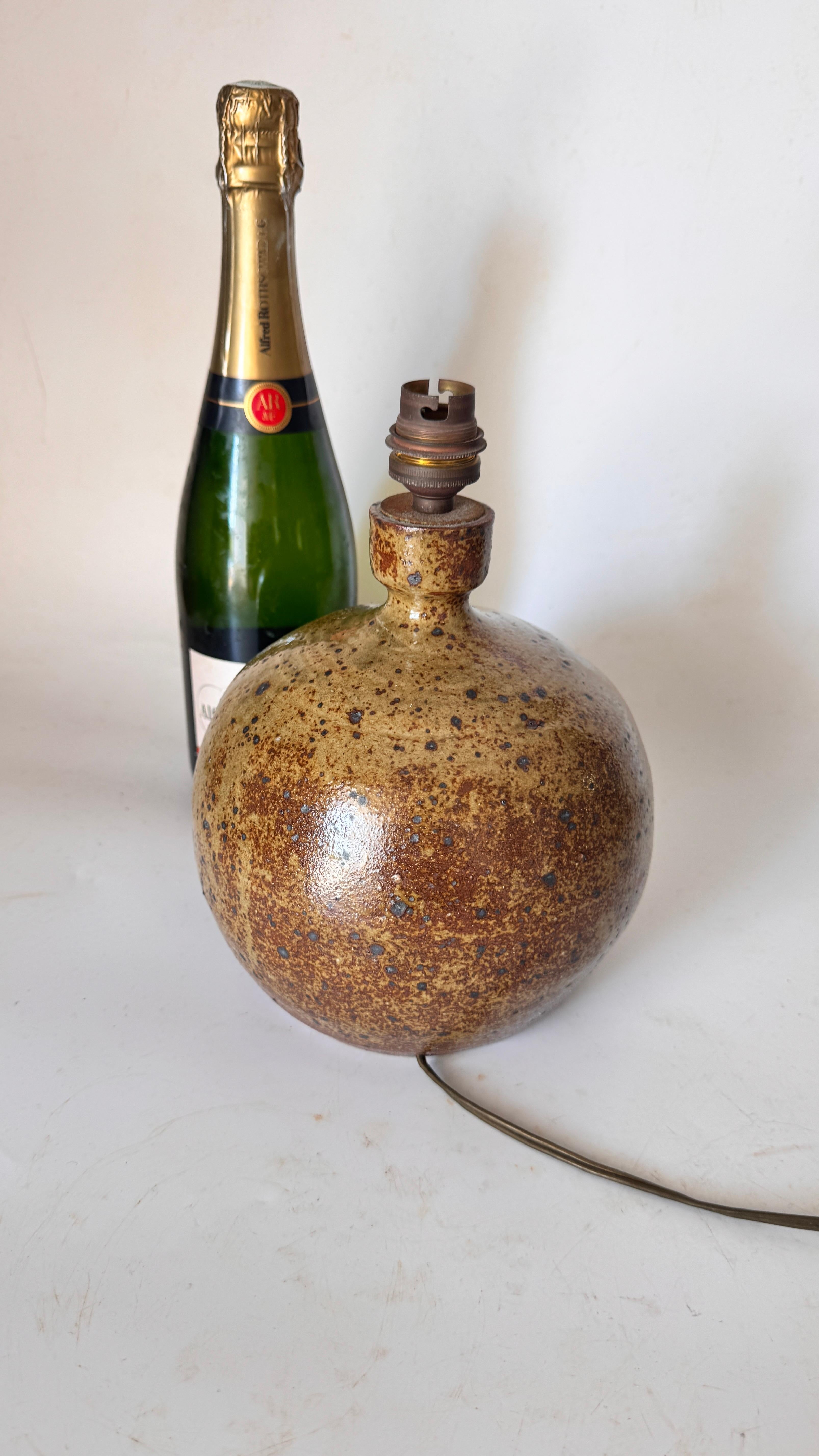 Si tratta di una lampada in gres degli anni '60, realizzata nel sud della Francia. Presenta un design minimalista con una palette di colori naturali: un mix di verdi e marroni, con superfici strutturate e leggermente granulose che catturano