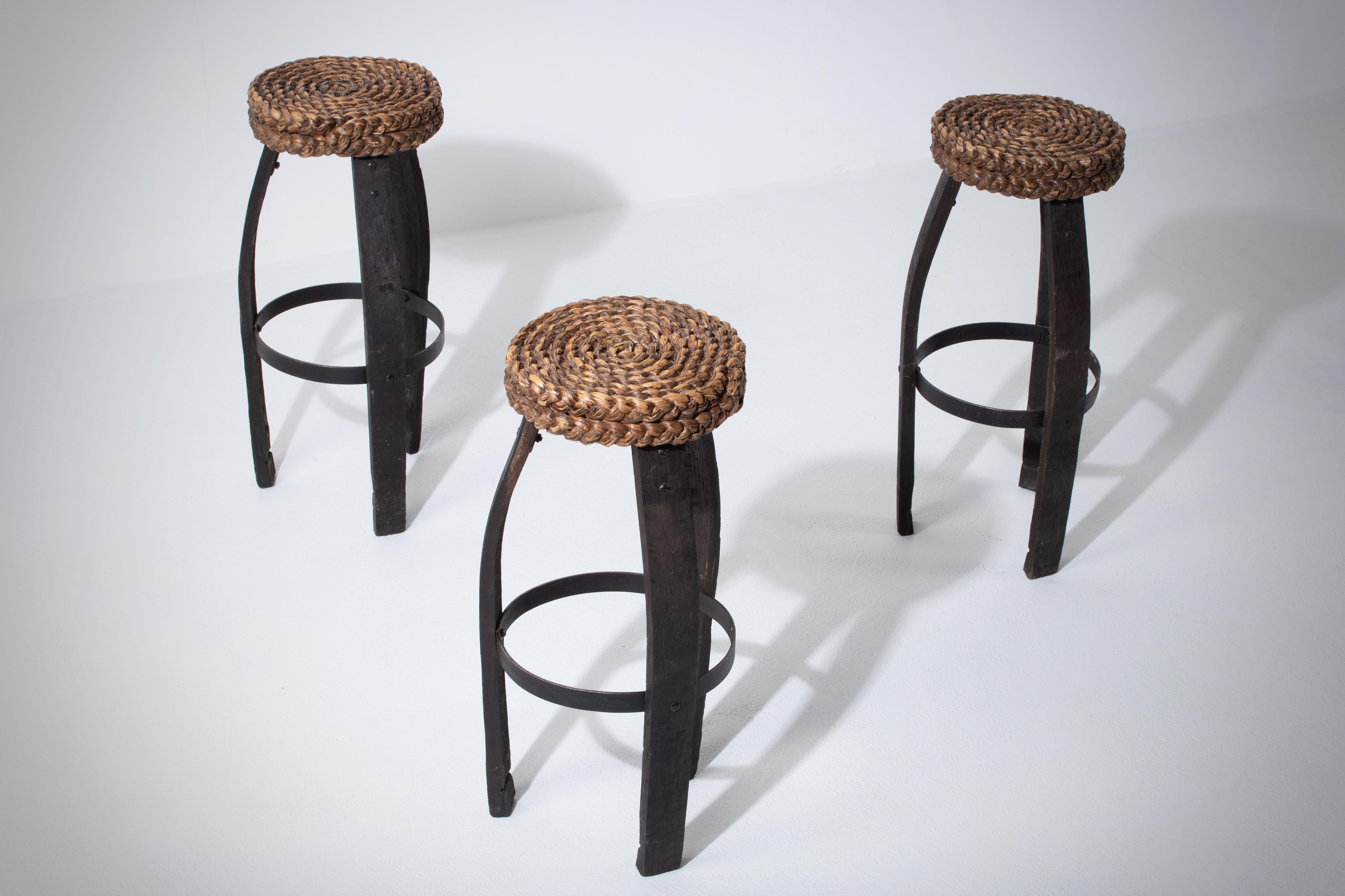Bar stool in oak with a woven cane seat by French designers Adrien Audoux and Frida Minet. France, 1950s.

The seat consists of thick, circular braided reed braids. Legs are made of dark oak and iron, which forms a perfect contrast to the seat.