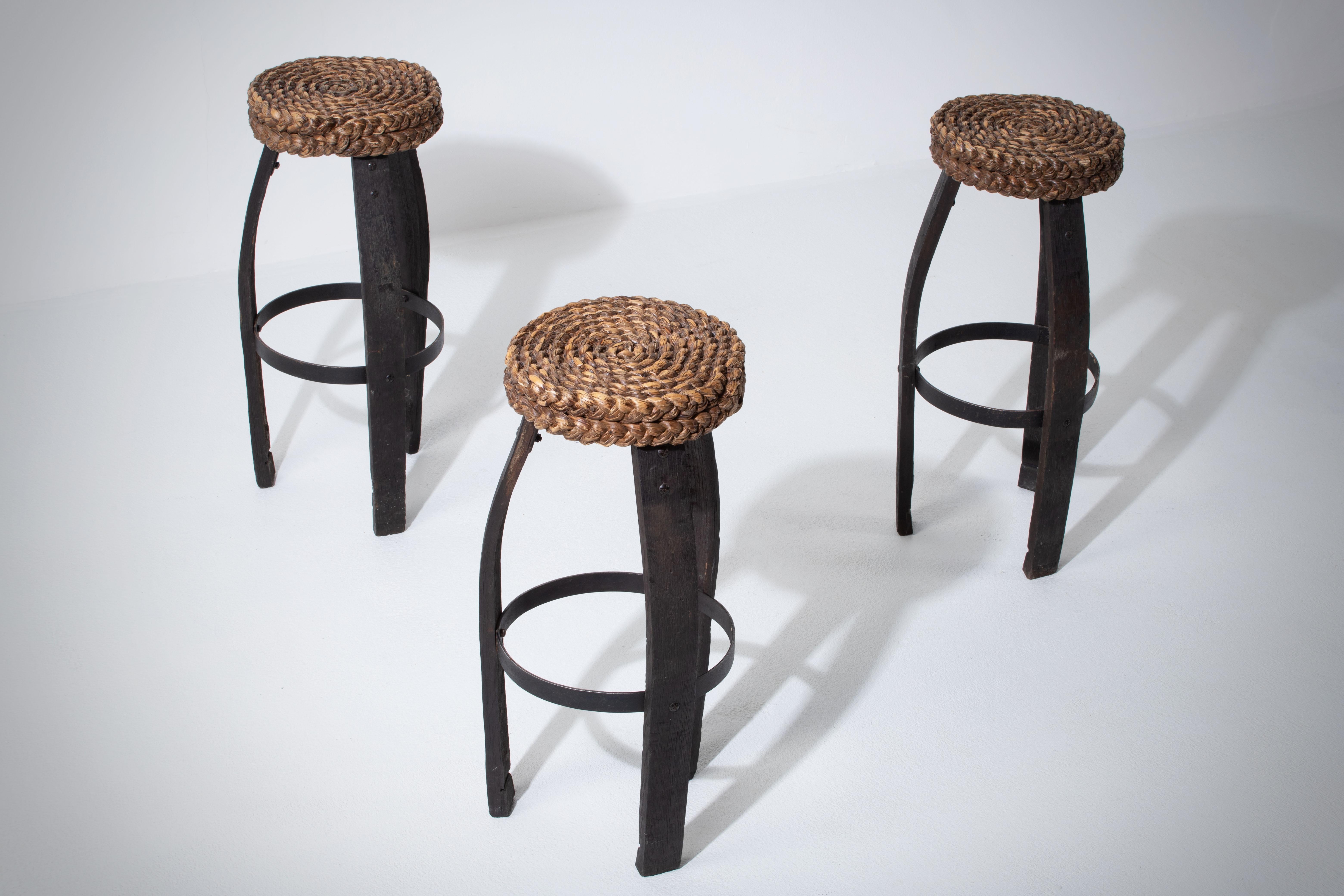 Sgabello da bar in Oak con seduta in canna intrecciata dei designer francesi Adrien Audoux e Frida Minet. Francia, anni '50.

Il sedile è costituito da spesse trecce circolari di giunco intrecciato. Le gambe sono in rovere scuro e ferro, in