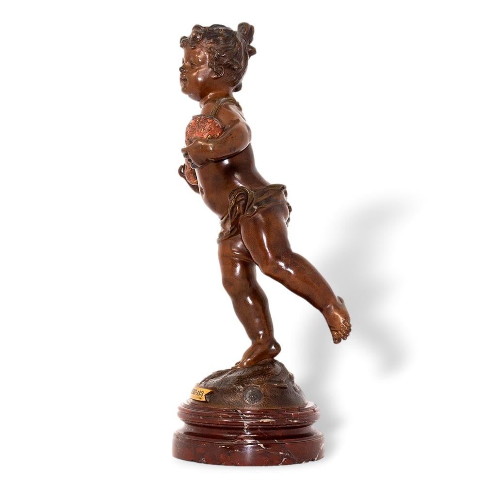 Ce modèle inhabituel en bronze datant de la fin du XIXe siècle représente un chérubin en bronze patiné tenant deux grosses fraises, la vigne s'enroulant autour du cou du chérubin qui se tient en équilibre sur un pied. Le bronze repose sur un socle à