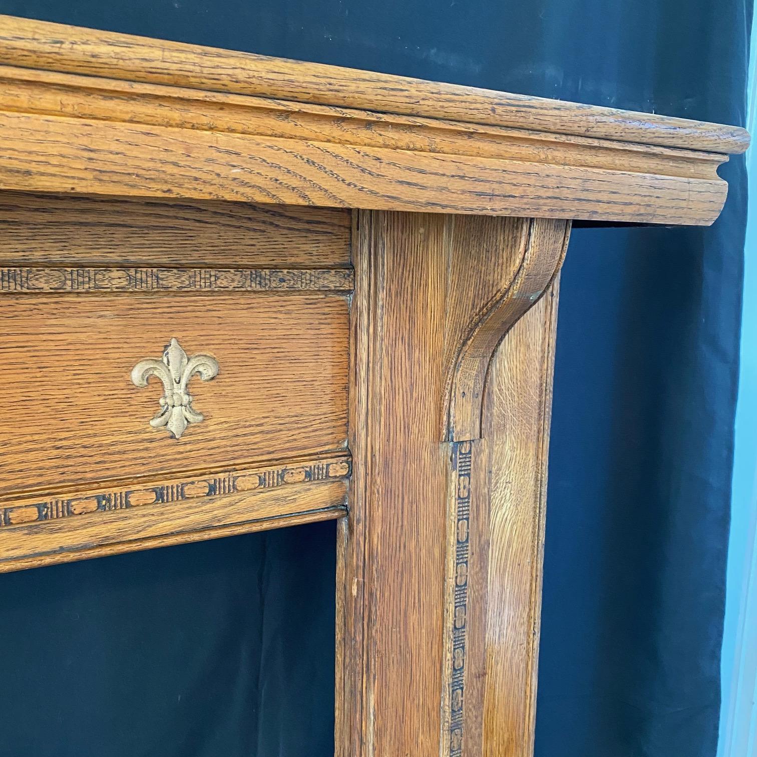 Beautiful French style carved oak mantel in the Art Nouveau genre, with lovely gold applique of crests and acanthus leaves. #5922

 H opening 35.5” W opening 35”.