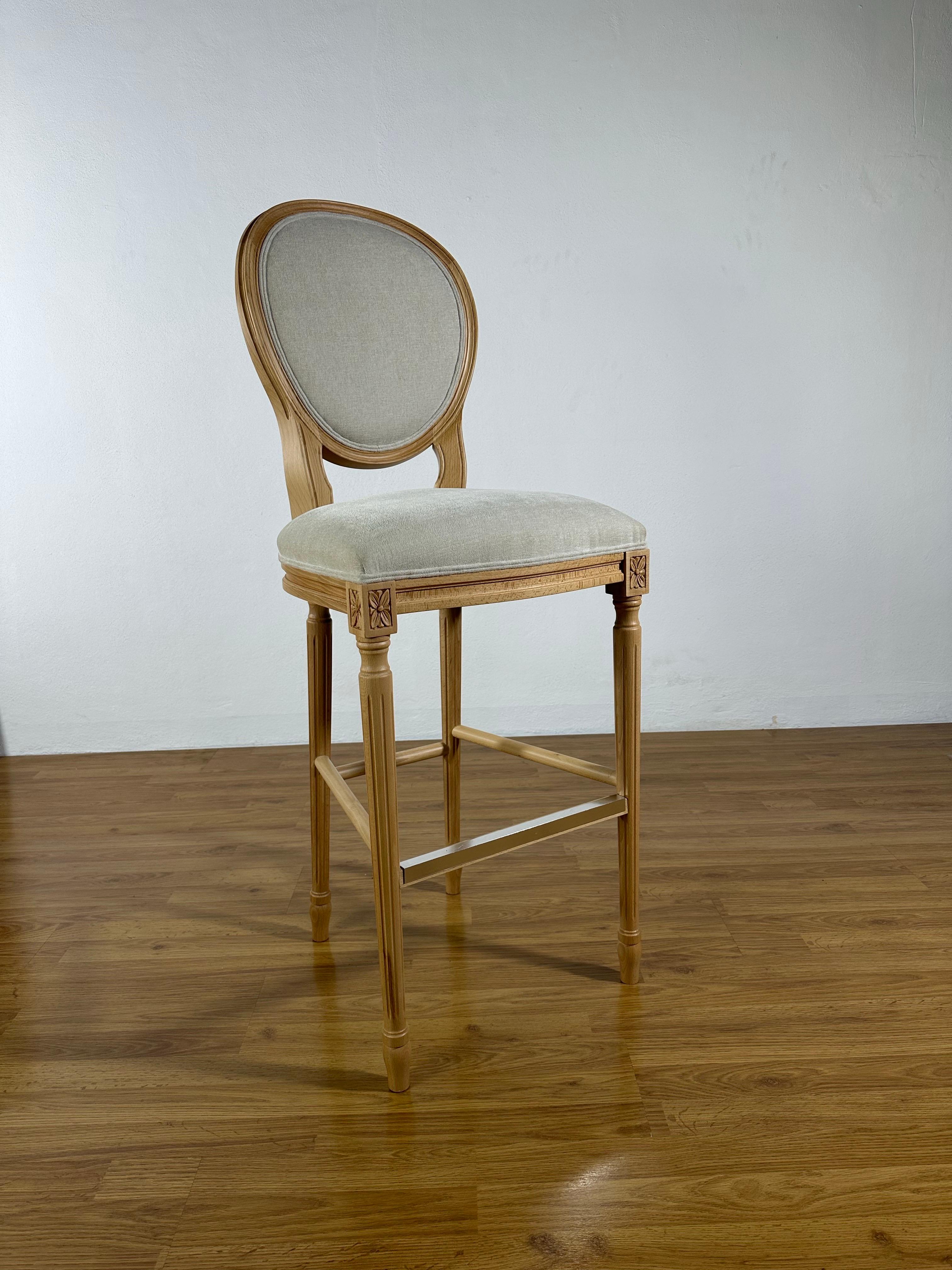 This exquisite French-style bar stool, crafted entirely in Spain, embodies timeless elegance and refined craftsmanship. Made from solid beech wood, it features graceful curves, delicate carvings, and an oval-shaped upholstered backrest that reflect