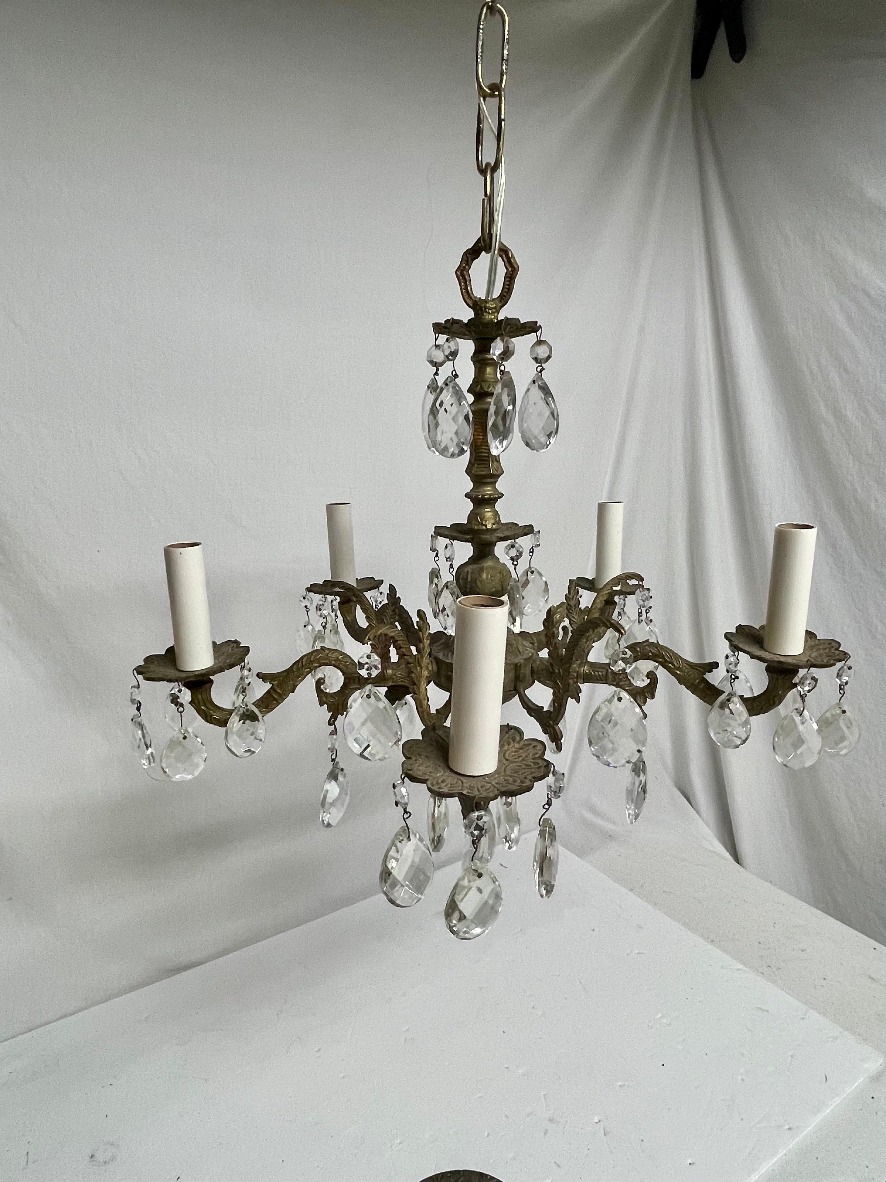 Brass and Crystal French Style Chandelier featuring two sizes of shimmering crystals mounted on a detailed brass frame. Rewired with clear wire. Five arms with candelabra sockets. New cream colored candle covers. Chandelier measures 17