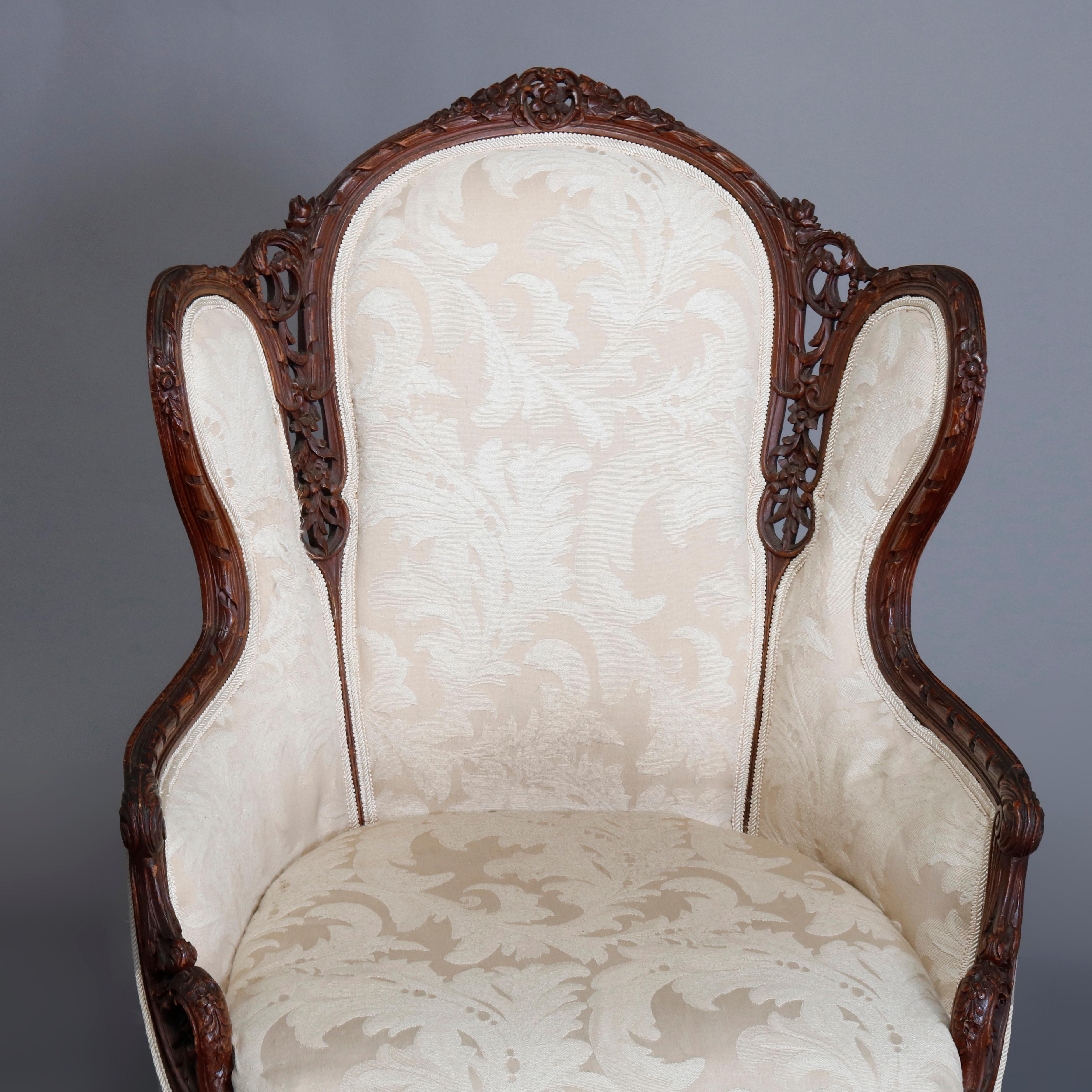 A French style fireside wing back chair offers carved and pierced foliate and scroll form frame with ?floral crest, upholstered seat and back and raised on cabriole legs, 20th century

***DELIVERY NOTICE – Due to COVID-19 we are employing NO-CONTACT