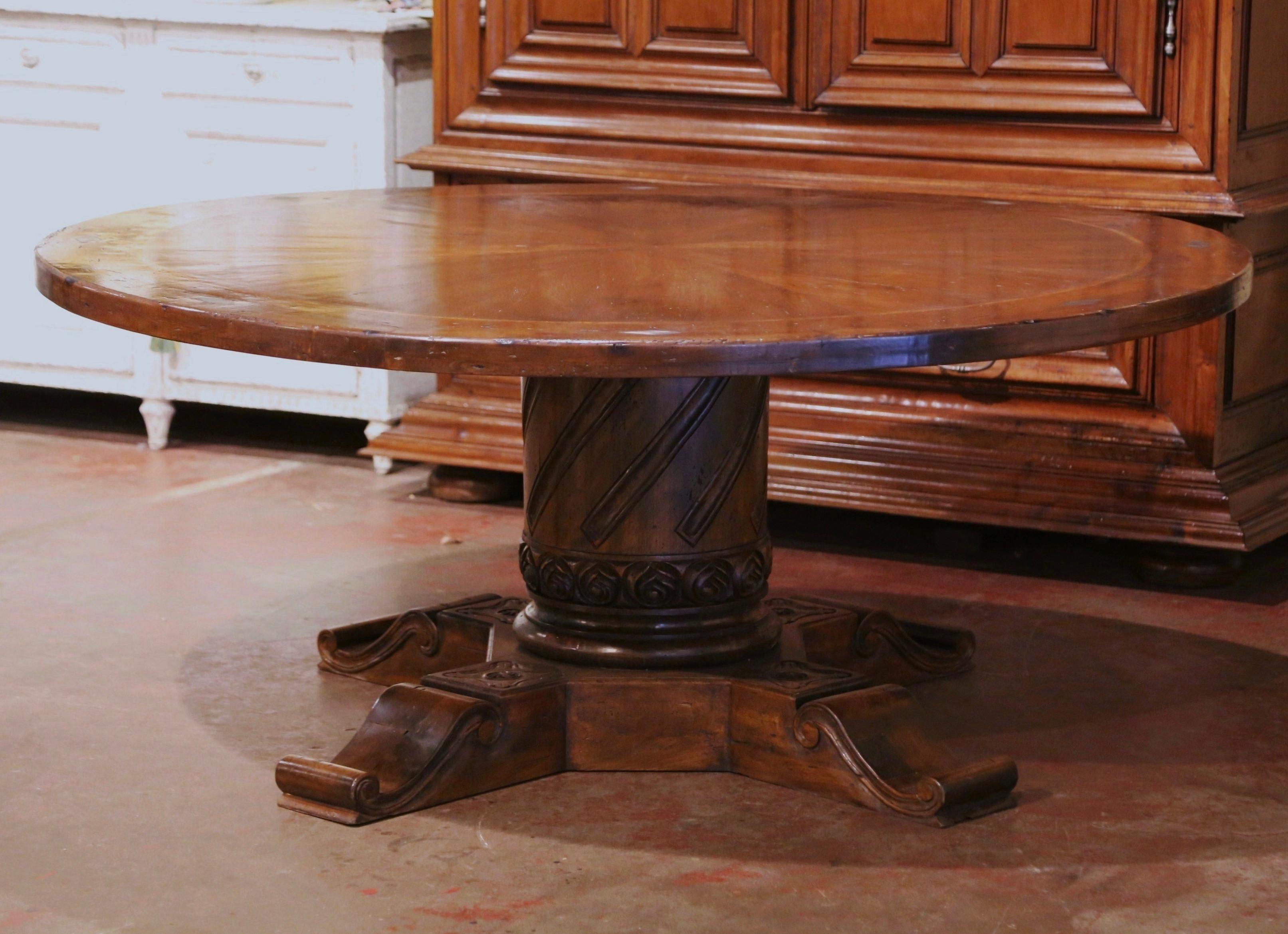 This large, hand-carved walnut dining room table would make an impressive addition to a dining room of any style. Crafted from a French Pyrenees design, the table stands on a thick hand carved column pedestal base supported with four flat feet