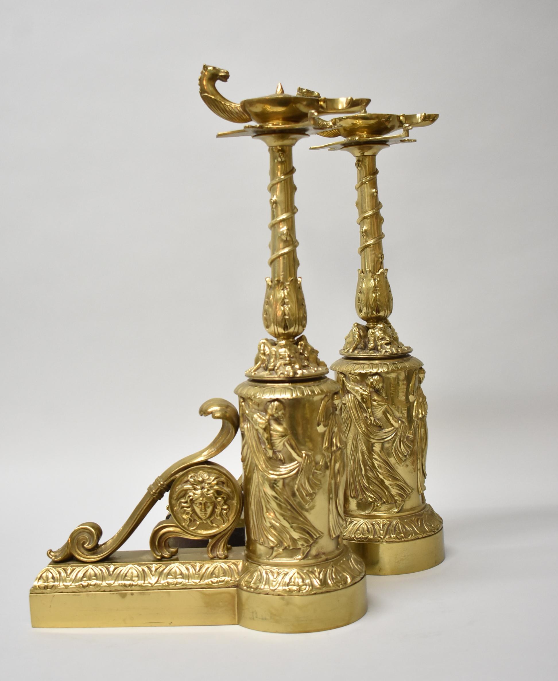 French style cast brass chenets / andirons with acanthus leaf details and raised medusa portrait. Figural horse head at top of finial. Base encircled by robed males and a relief of Bacchus.