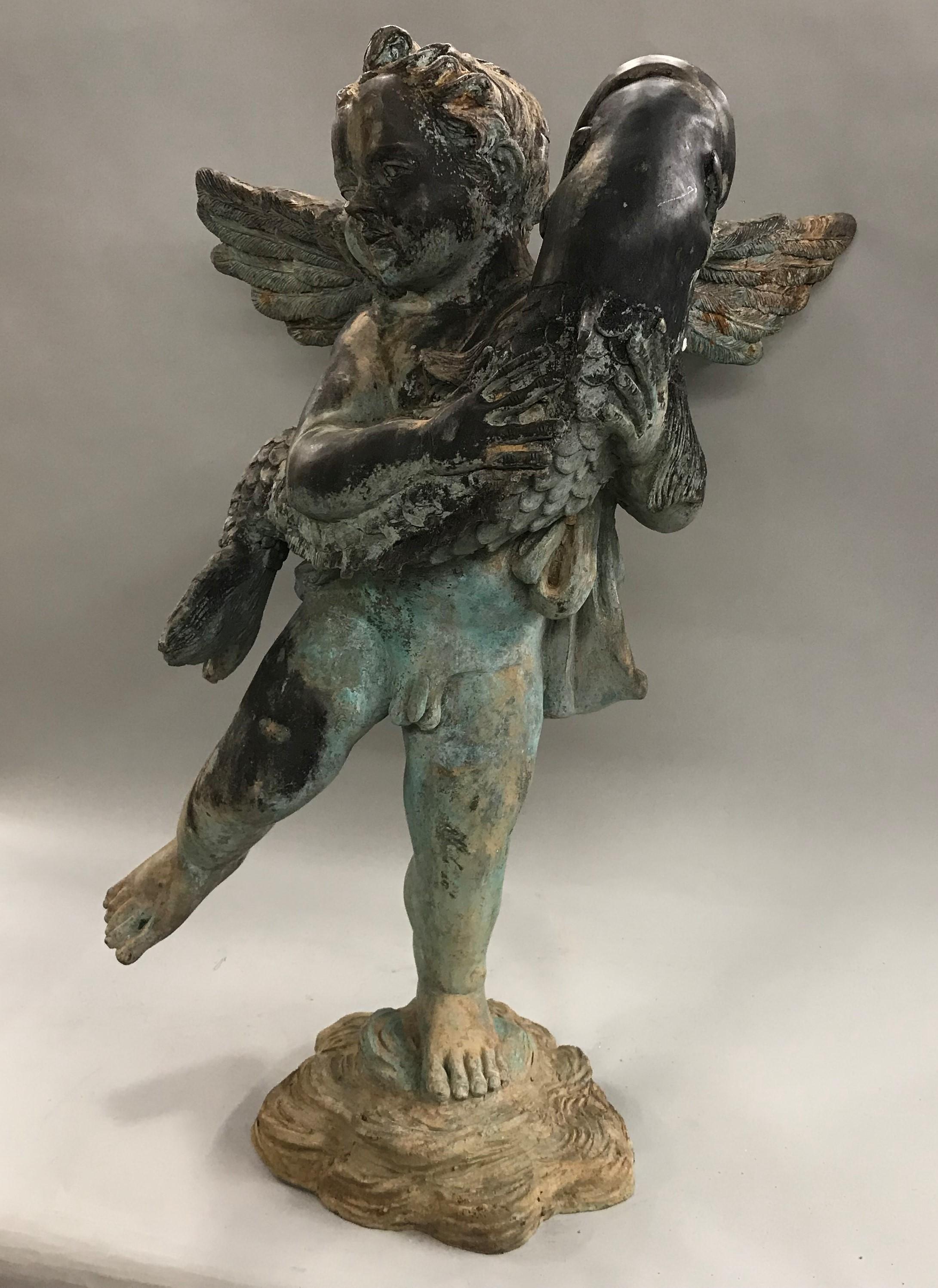 A fine French style cast iron fountain depicting a winged cherub or putti holding a large fish, dating to the 20th century. Great overall patina, with minor soiling, spot rusting, and expected wear from exterior use. Dimensions: 30.5 in H x 25 in W
