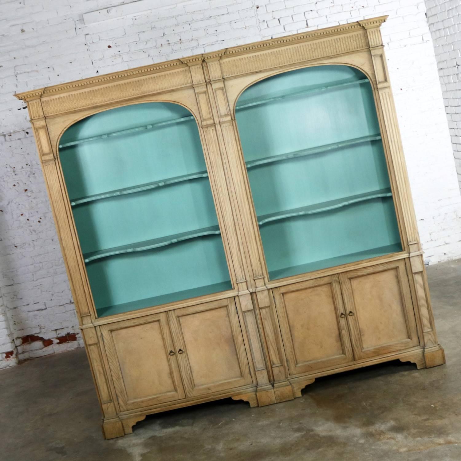 Handsome French style cerused open bookcases with turquoise interior and doored bottom cabinets by Baker Furniture. Two individual cabinets that are bolted together to form one piece. They are in fabulous vintage condition with normal wear and no