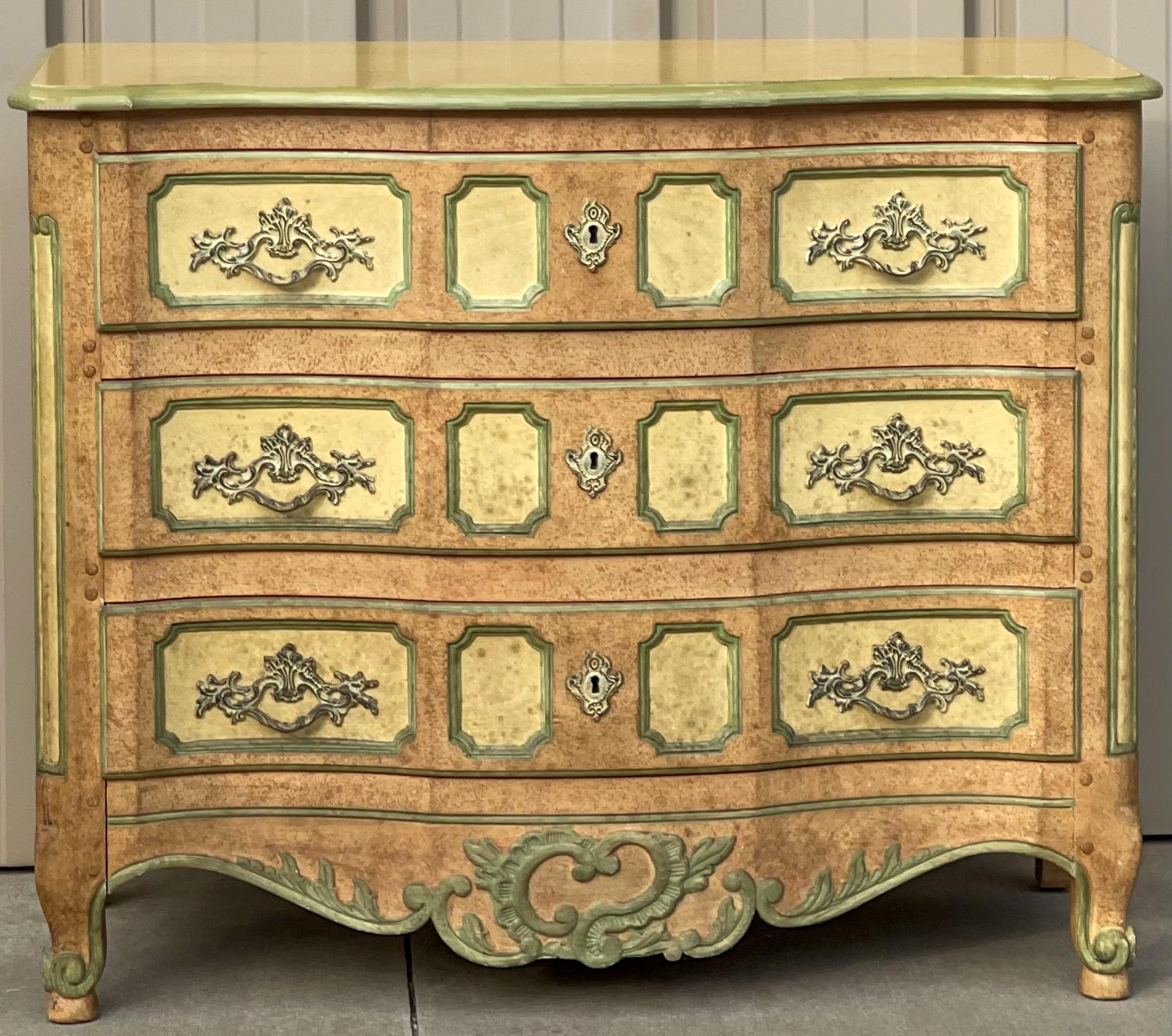 This is a custom painted commode by Baker Furniture Company. It is marked and in very good condition. The piece is a heavily carved fruitwood, and the painted finish is a vintage one.