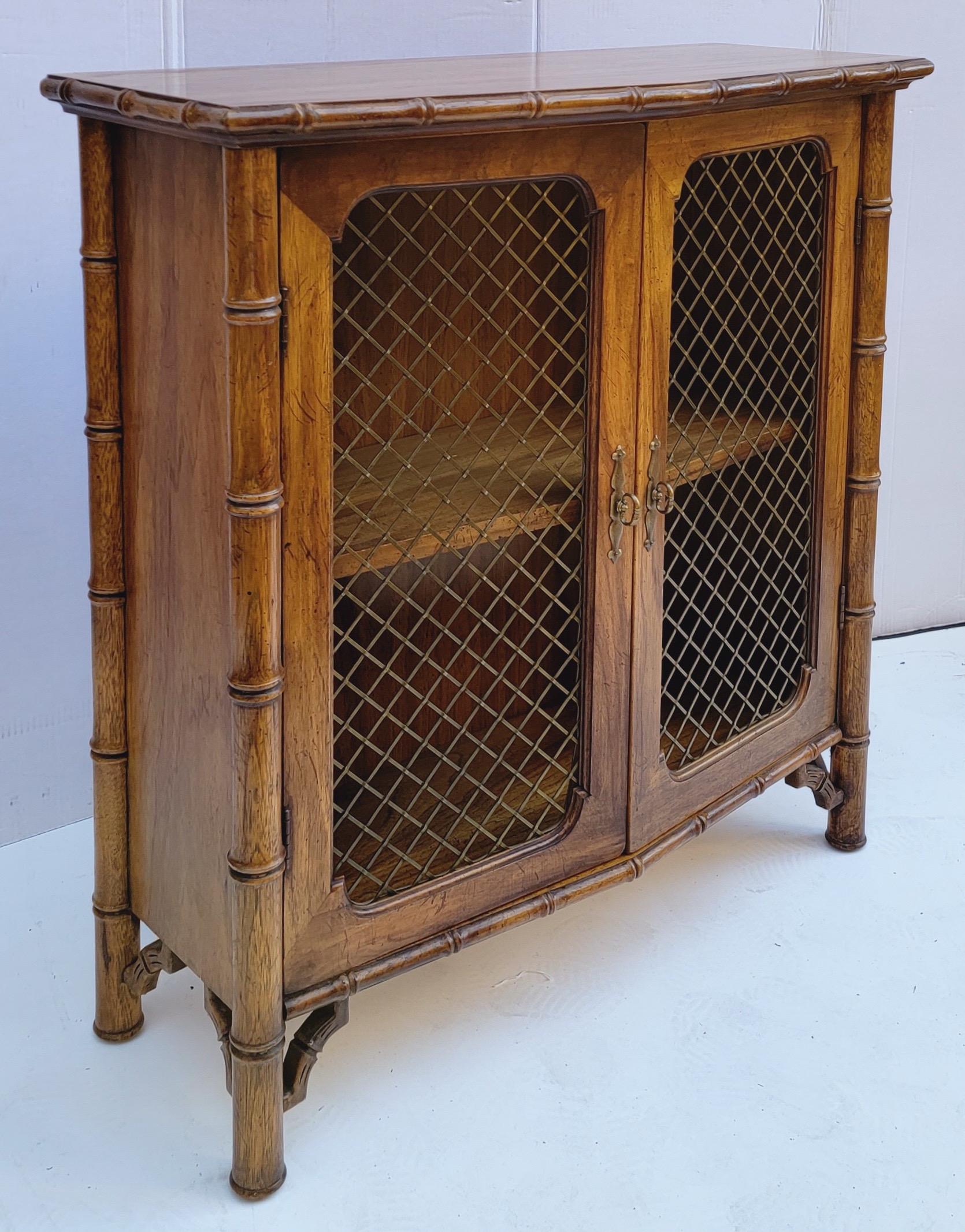 This is a great little bookcase! It has a carved fruitwood faux bamboo frame and wire doors. It is unmarked and in very good condition. I believe this to be from the 60s/70s. Note that it bows out to a rounded point.