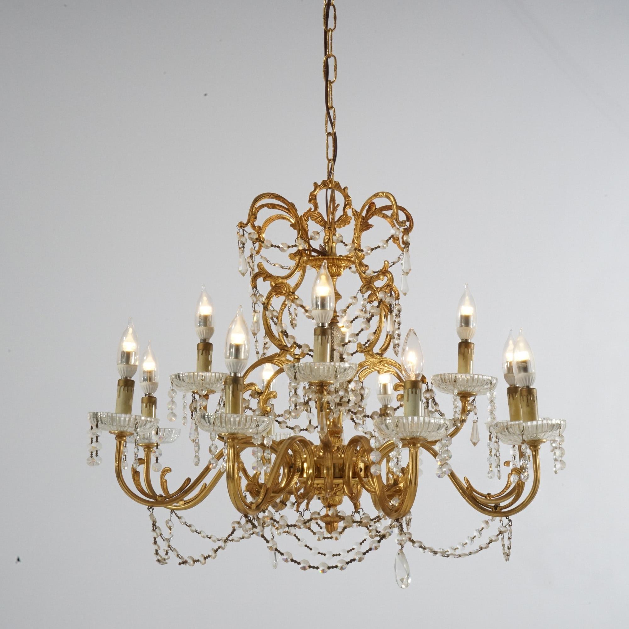 Ein antiker Kronleuchter im französischen Stil hat einen vergoldeten Rahmen mit verschnörkelten, blattförmigen Armen, die in zwölf Kerzenlichtern enden, sowie aufgereihte und tropfenförmige Kristalle, um 1930

Maße: 38''H x 26,5''B x 26,5''T;