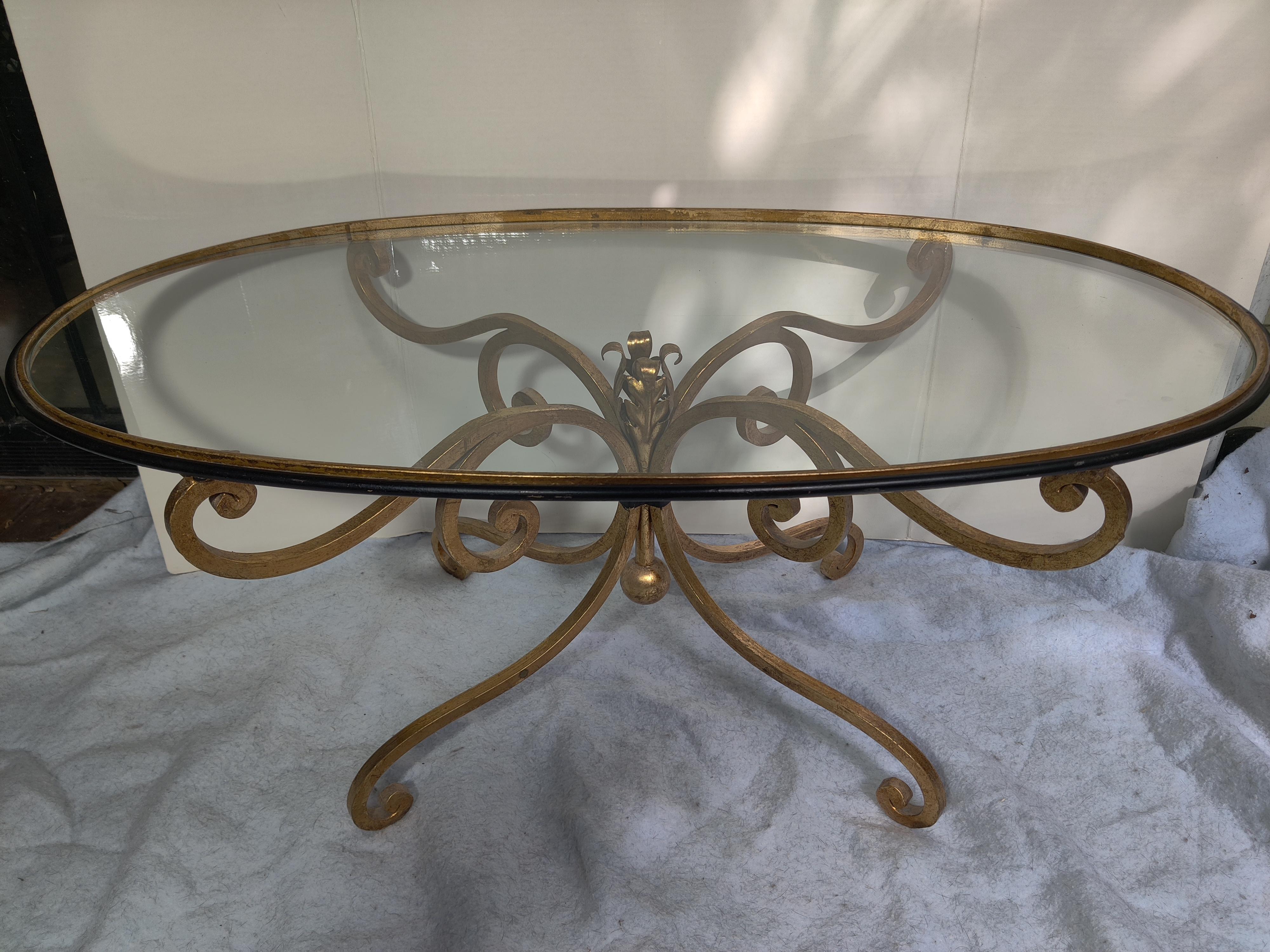 French Style Iron Gold Oval Coffee Table.  1960's - 1970's
Black and gold at side of table.   Small areas where black and gold paint are worn but in good condition. 
Glass has a few minor scratches, no chips.
Glass is inserted in a frame at top of