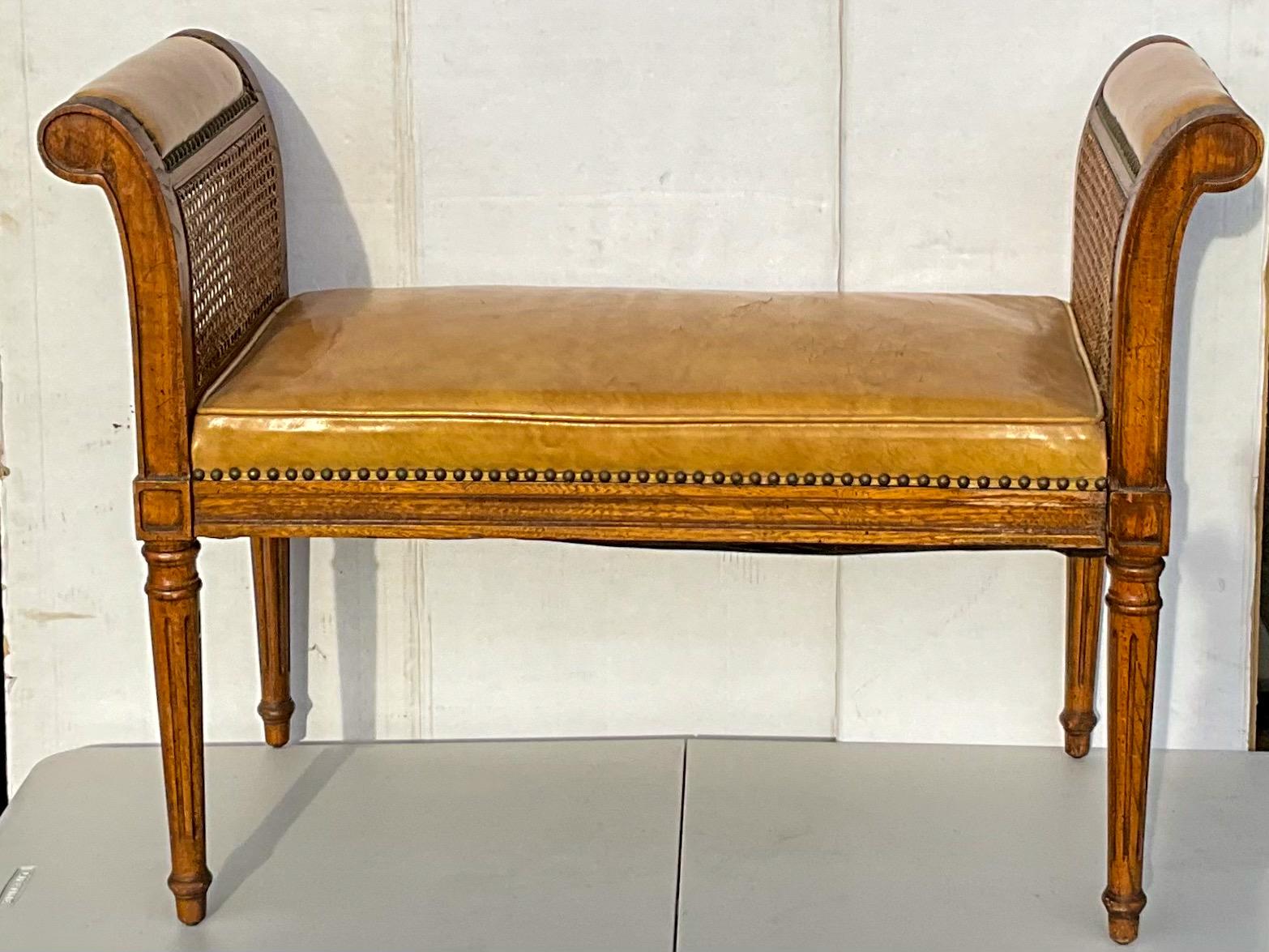 This is a handsome Italian walnut and leather bench with French styling. It has caning on both supports with leather arm rests. Brass nailheads complete the look. The gold leather shows some age wear but does not detract from the beauty. It is