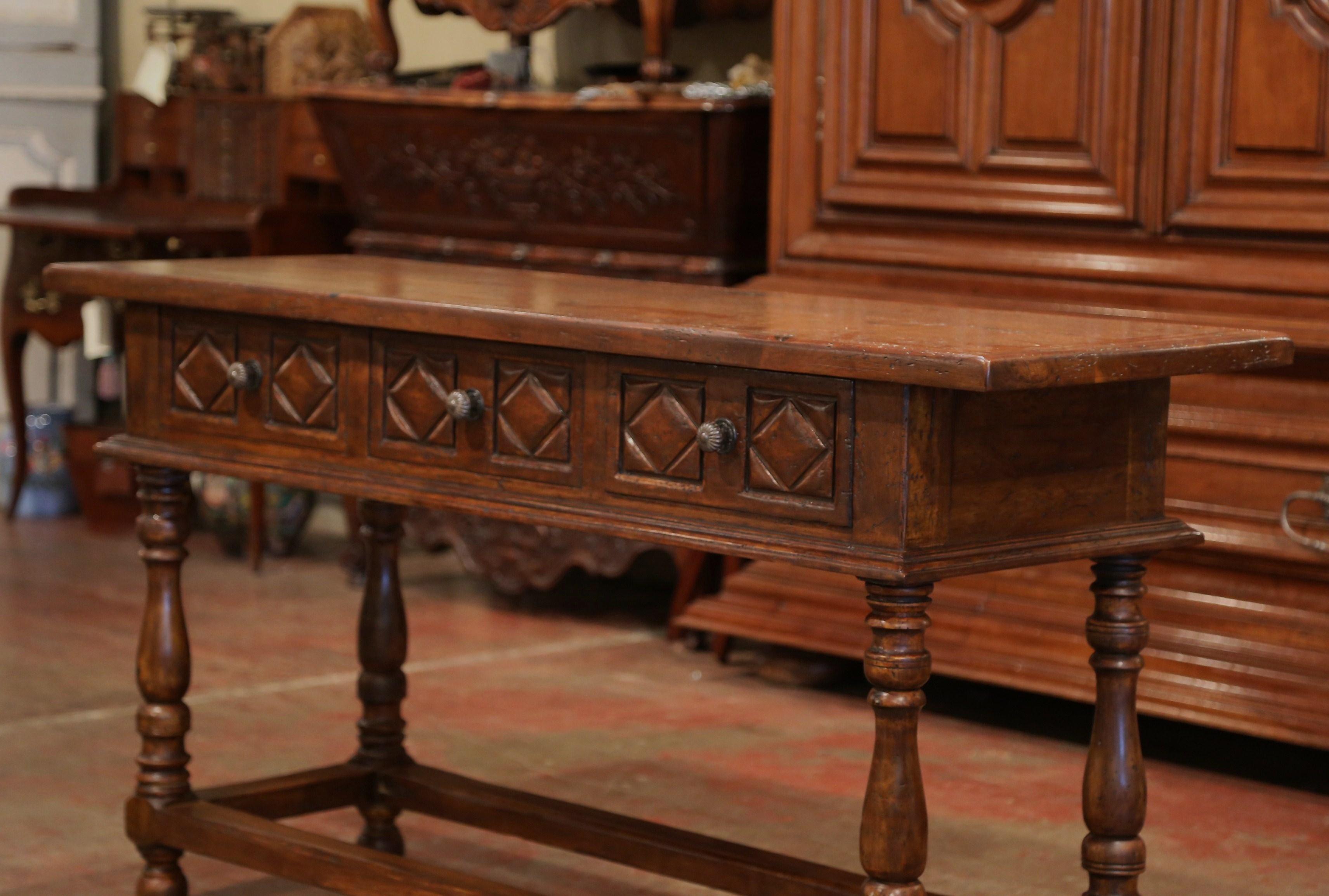 Place this elegant console table behind a sofa or against a wall. Crafted after an original found in the Pyrenees of France, the narrow fruitwood sofa table sits on four turned legs with a bottom stretcher, and features three hand carved drawers