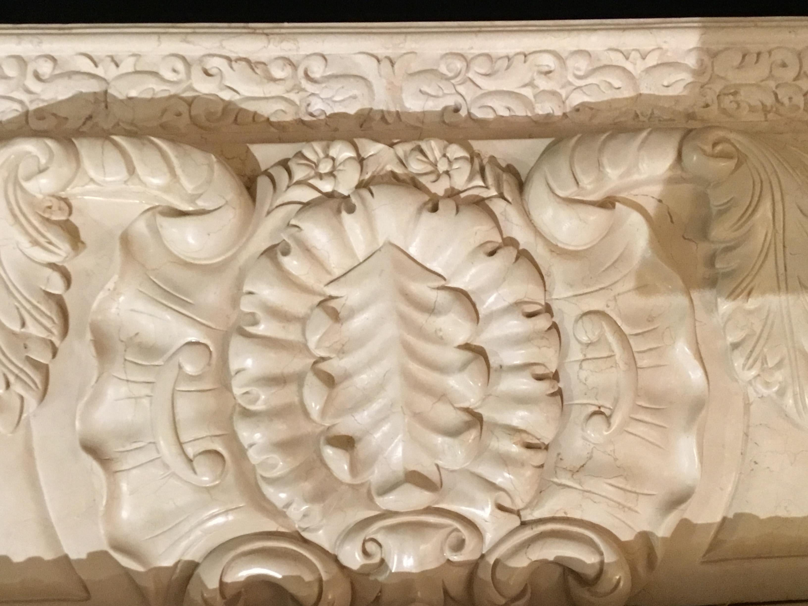 Large cream color marble mantel that is hand carved with floral and foliate designs. Petite flowers
Are carved in a horizontal line beneath the top piece and a vertical line down each side. A central
Leaf cartouche is centered at the top portion
