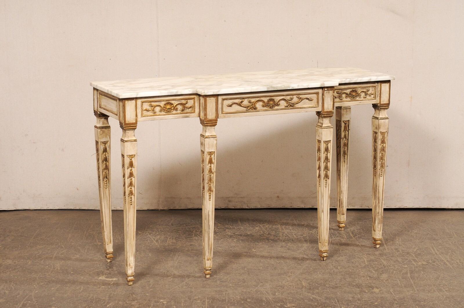 A vintage American carved-wood, breakfront console table with marble top and single drawer. This lovey table has been designed with French influences; featuring a marble top with break-front design (which carries down the front apron and