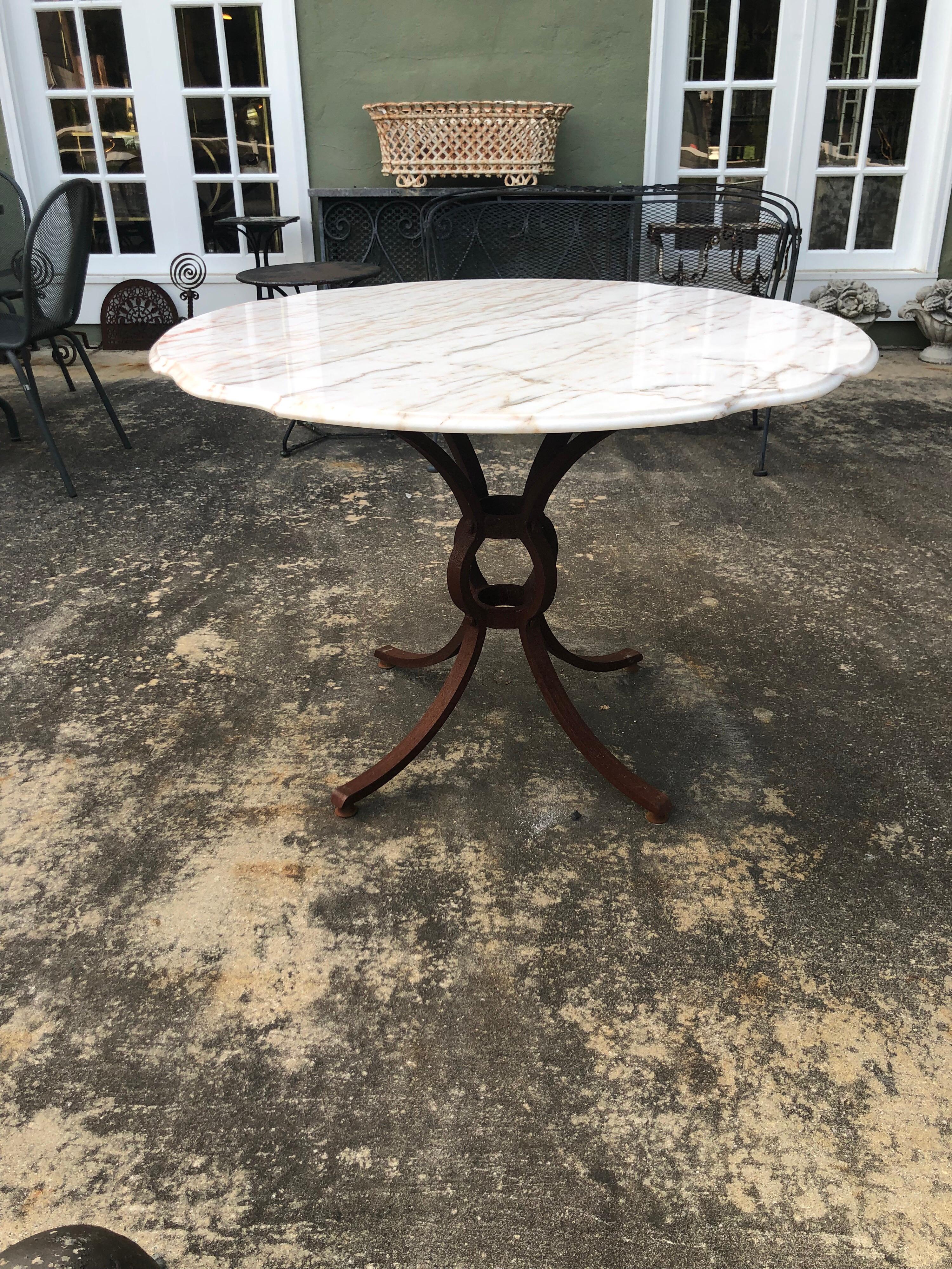 French style marble-top iron dining table. Heavy weathered Iron base most likely hand forged and one of a kind. Marble top is weathered too from being outside. Marble is stamped made in Belgium. The marble top has wooden underside base which screws