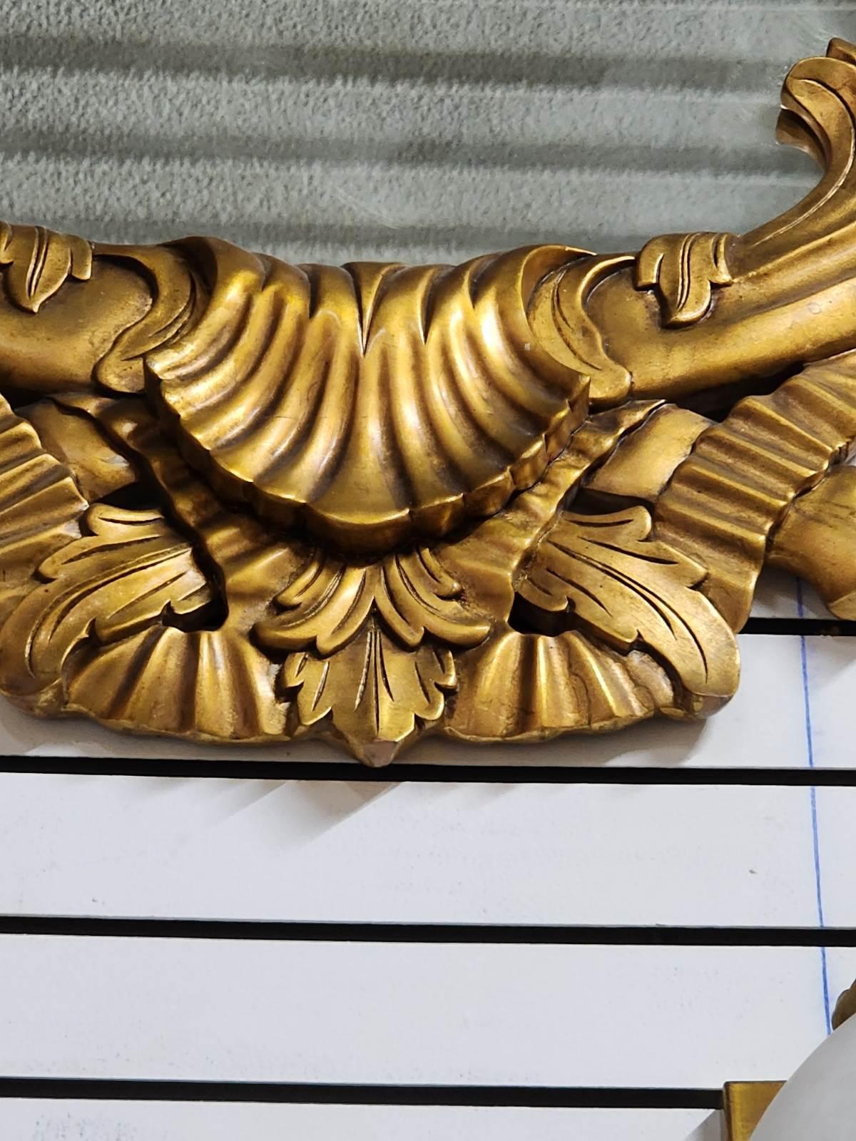 Specchio in stile francese con cornice dorata e bordi decorati. 
