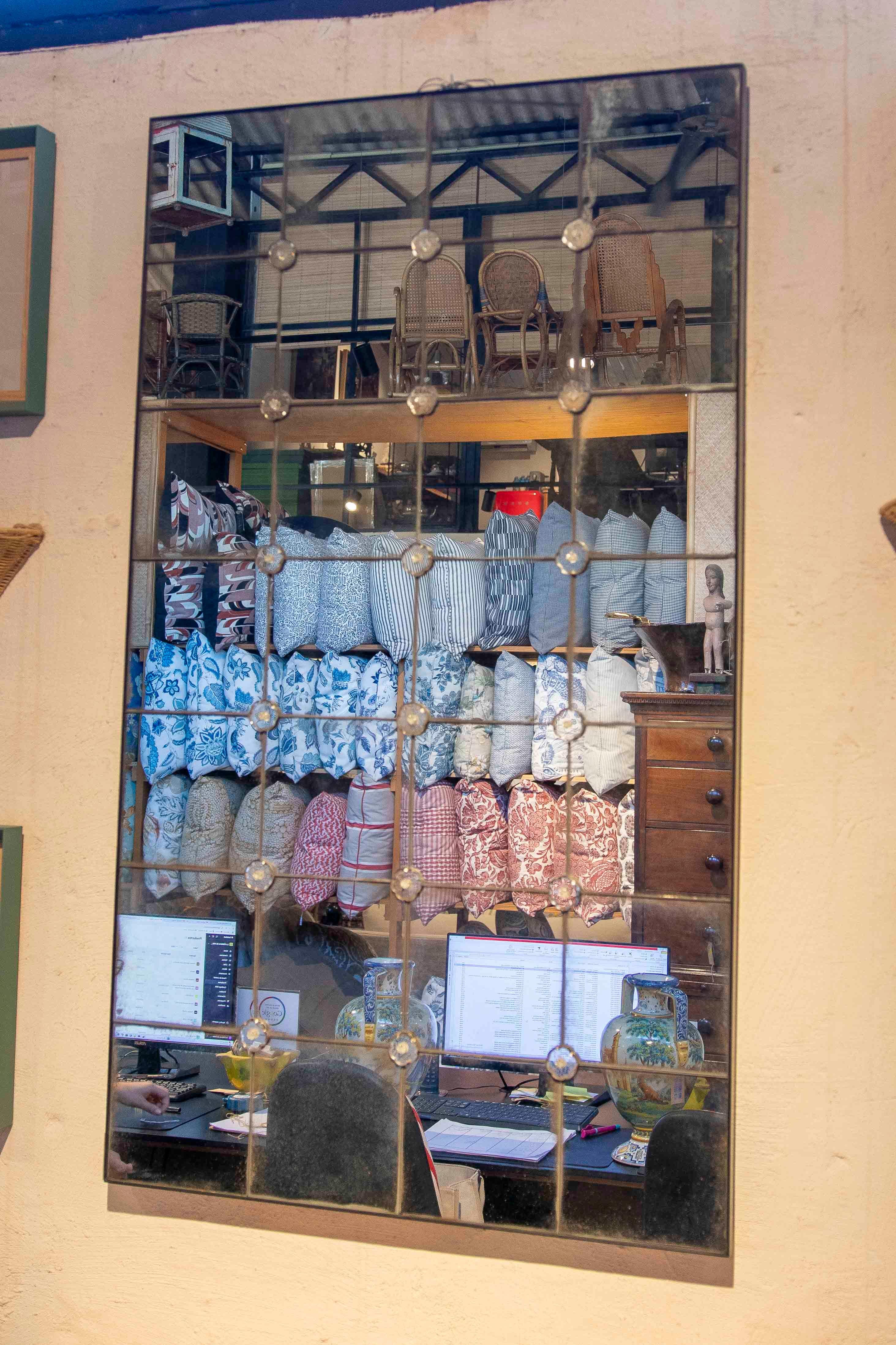 Wall mirror composed of multiple panels of aged glass, arranged in a grid pattern and joined by delicate floral fused glass appliqués. Its geometric and symmetrical design, combined with the mirror's oxidized effect, gives it a distinctive character