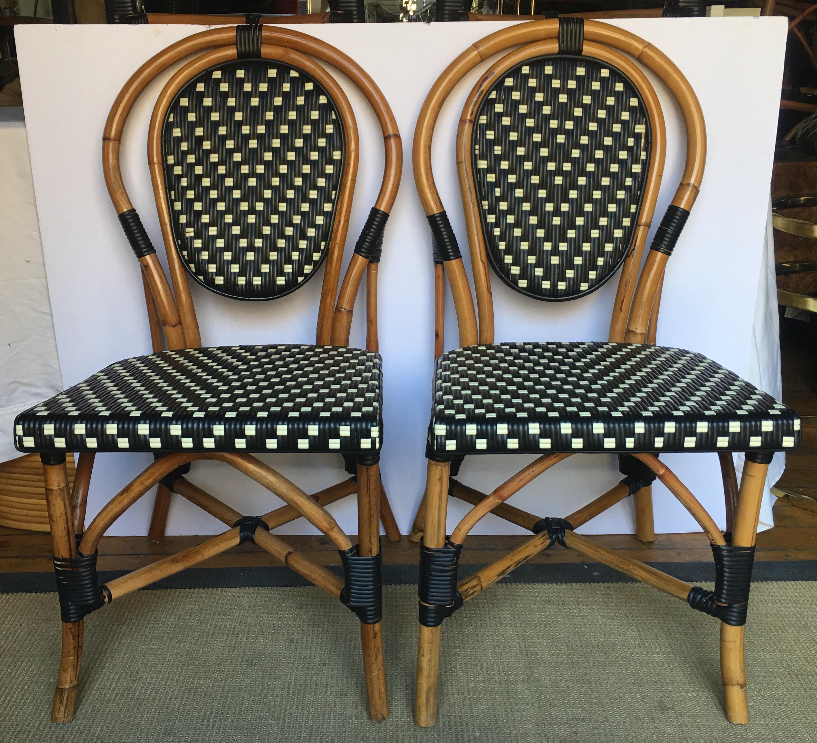Set of four Classic French style bistro dining side chairs just like those you find in a Paris café. Frames expertly handcrafted of natural Malacca/Manau steamed bent cane with neutral black/ivory woven nylon seats and backs. For indoor and outdoor