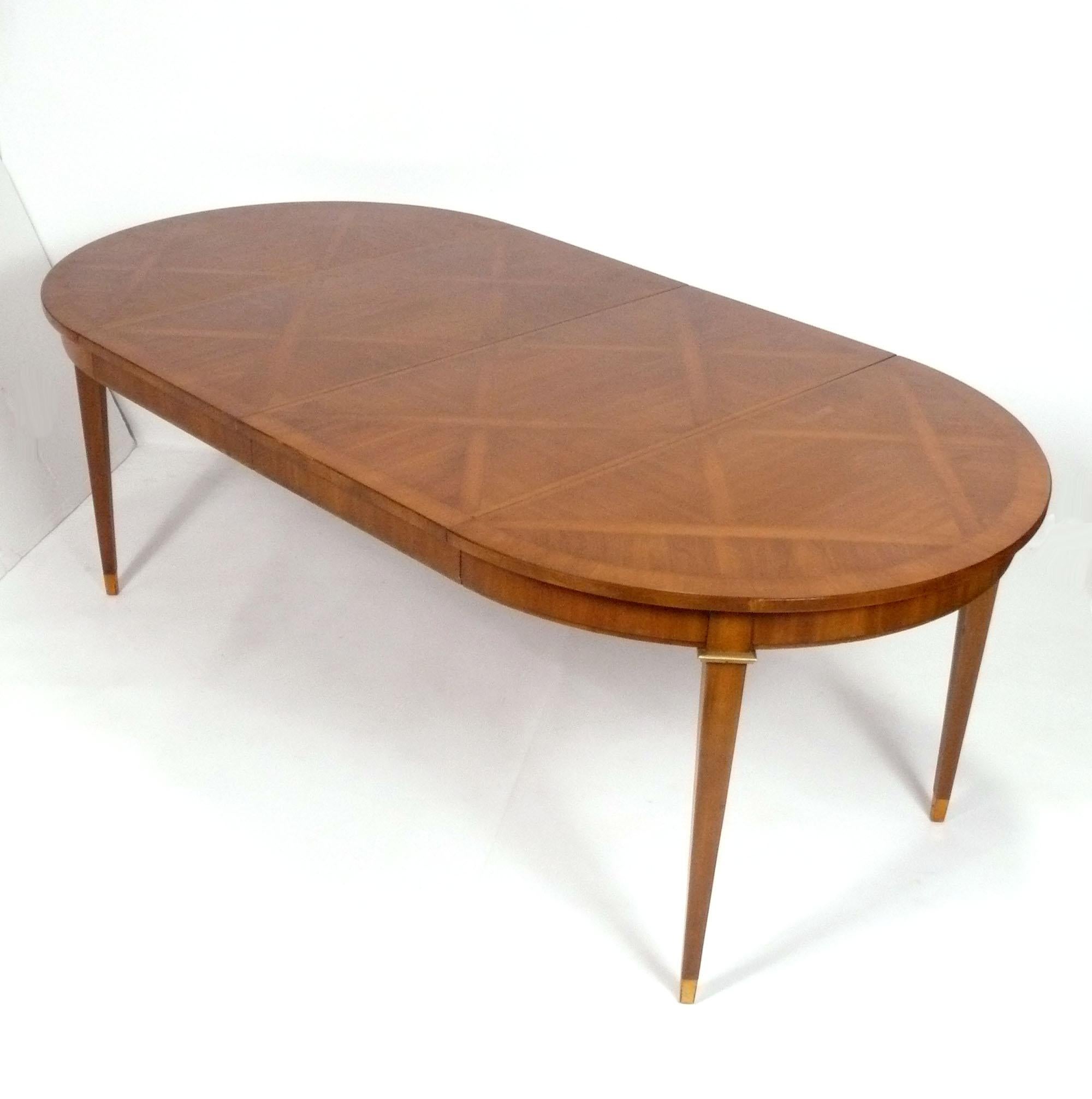 Elegante mesa de comedor de parquet, de estilo francés, probablemente estadounidense, hacia los años 50. Tiene un tamaño versátil y puede utilizarse como mesa de comedor, de desayuno o de juegos. Incluye dos hojas de 19,5