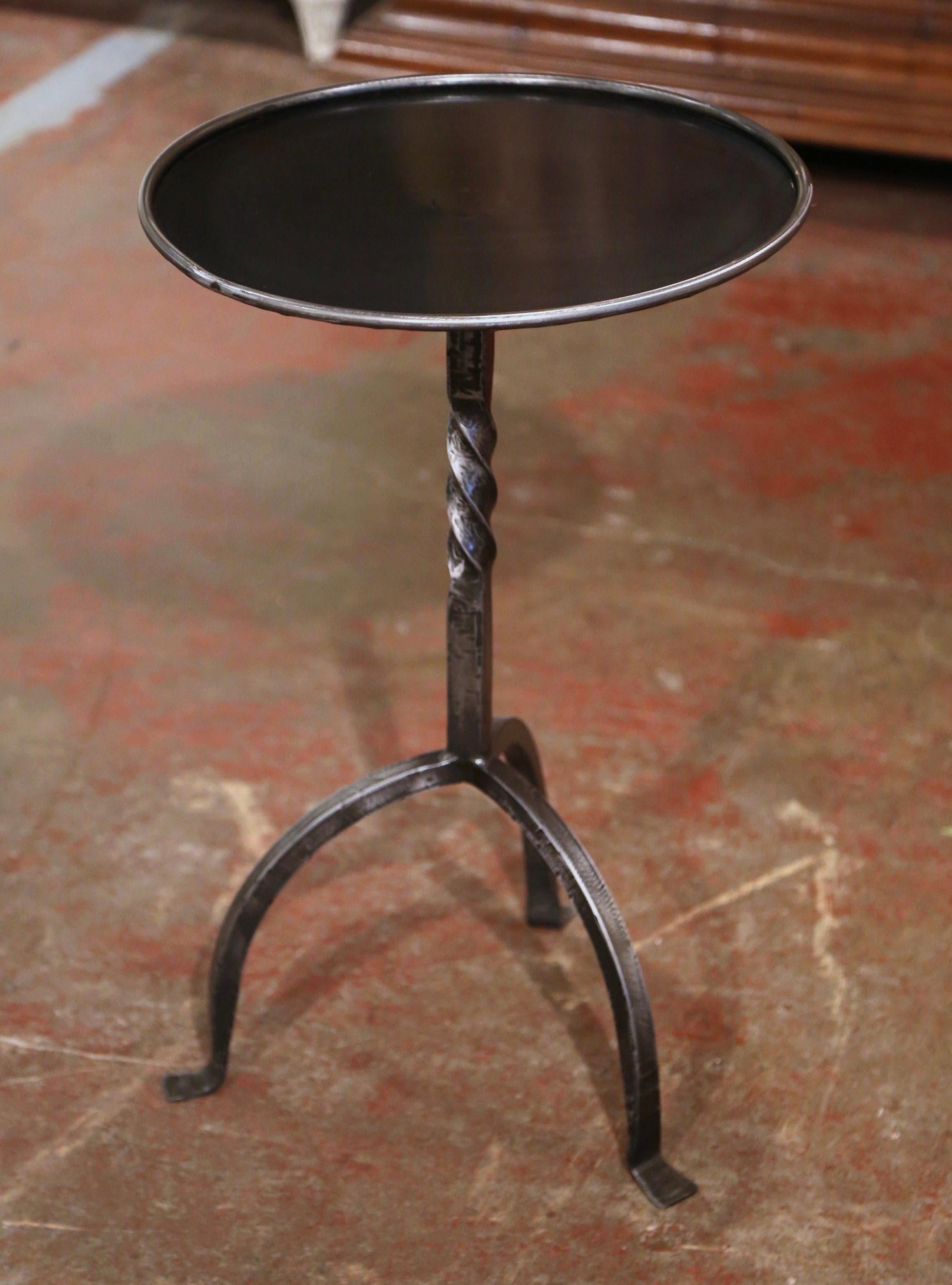 The elegant martini table features a central twisted pedestal stem over three curved legs ending with small feet. The vintage serving table is topped with a round surface decorated with a raised rim around the periphery. The chic, sophisticated