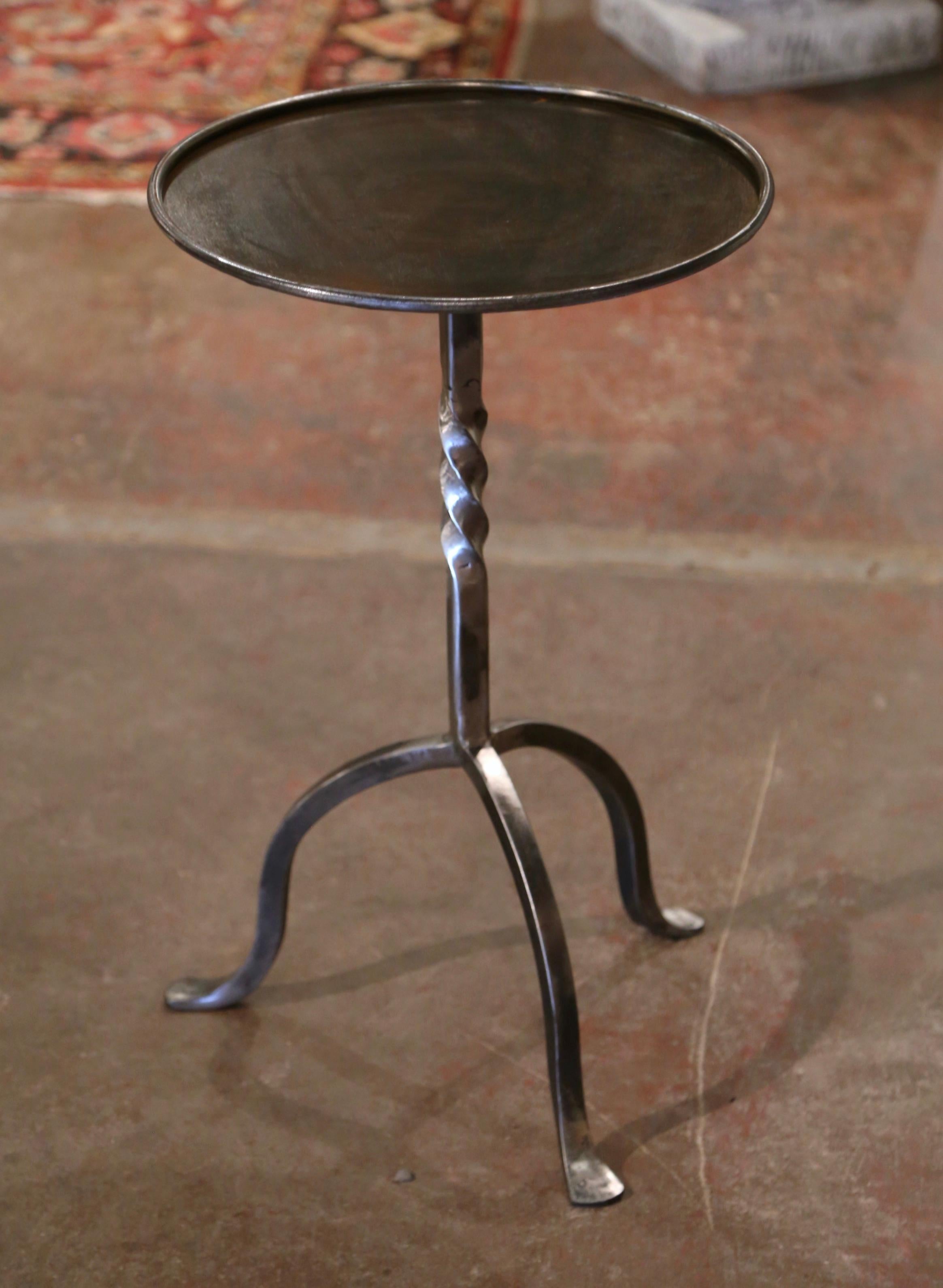 The elegant martini table features a central twisted pedestal stem over three curved legs ending with small feet. The vintage serving table is topped with a round surface decorated with a raised rim around the periphery. The chic, sophisticated