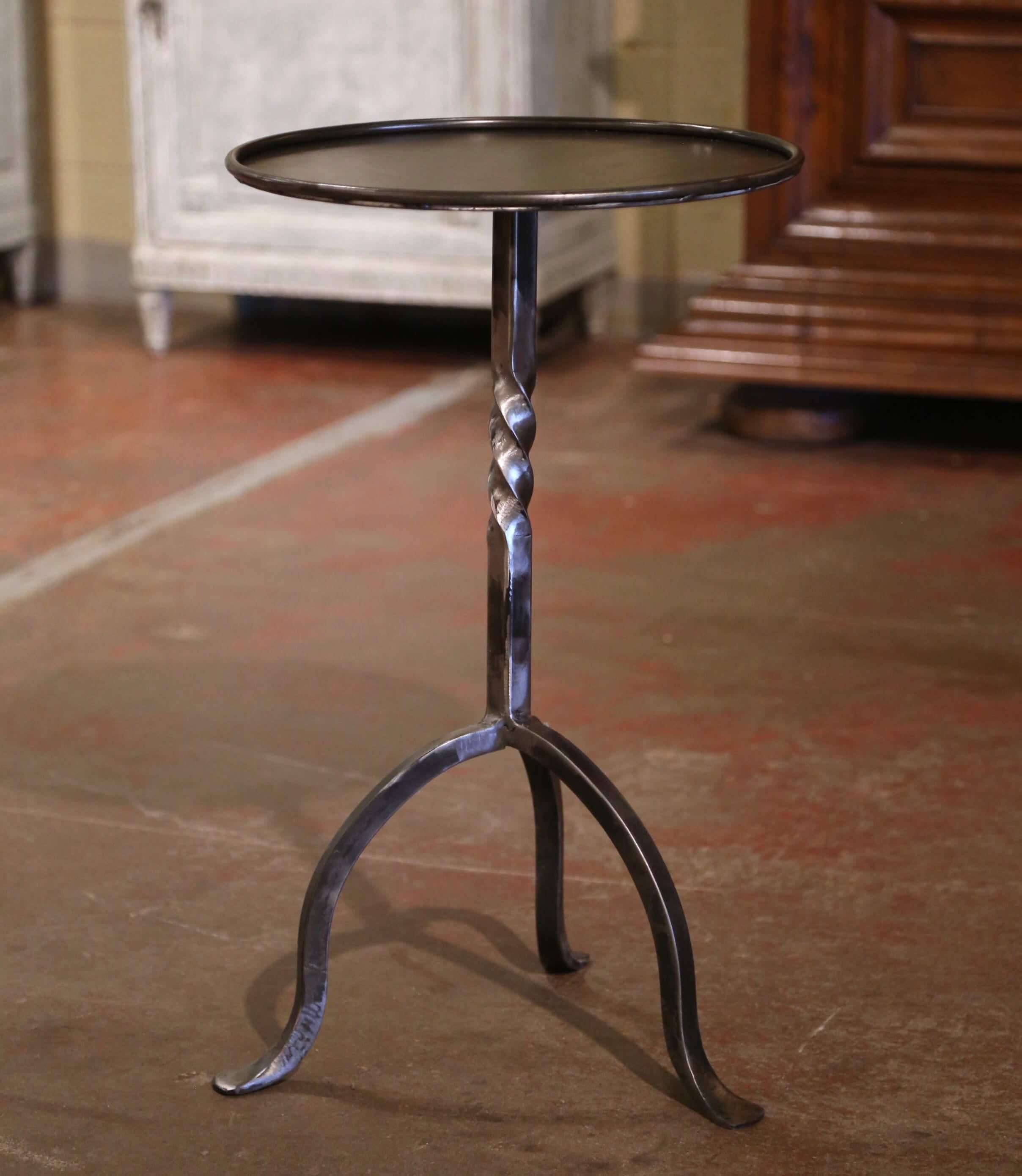 The elegant martini table features a central twisted pedestal stem over three curved legs ending with small feet. The heavy vintage serving table is topped with a round surface decorated with a raised rim around the periphery. The chic,