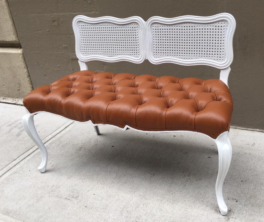 Has a white painted wood frame, a tufted vinyl seat and a caned back.