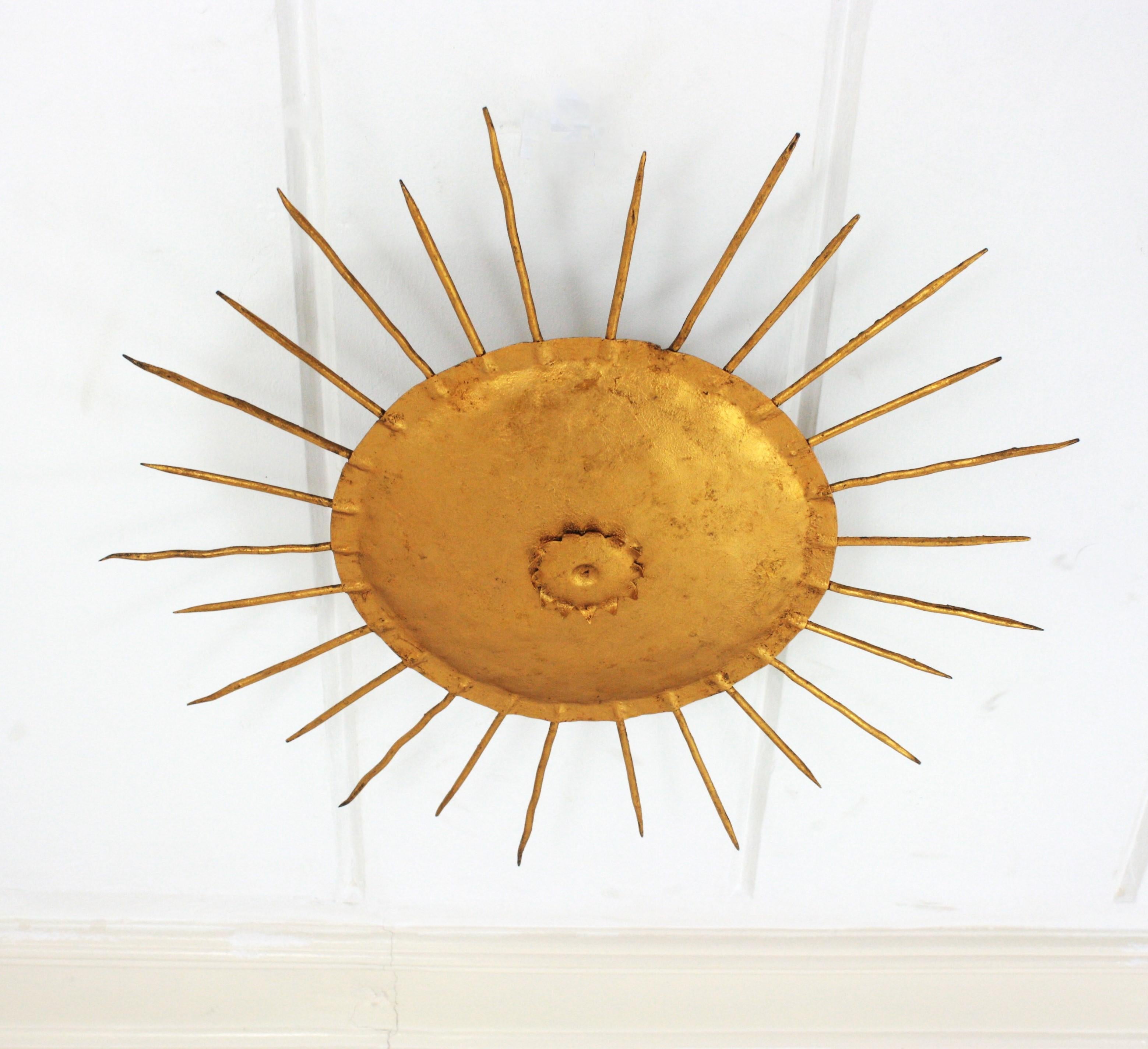 French Sunburst Ceiling Light Fixture in Gilt Wrought Iron, 1940s

1940s Gilt sunburst light fixture, wrought iron, France
This iron sunburst ceiling flush mount was hancrafted at the Art Deco period. It has a nice design with pointed spikes and a