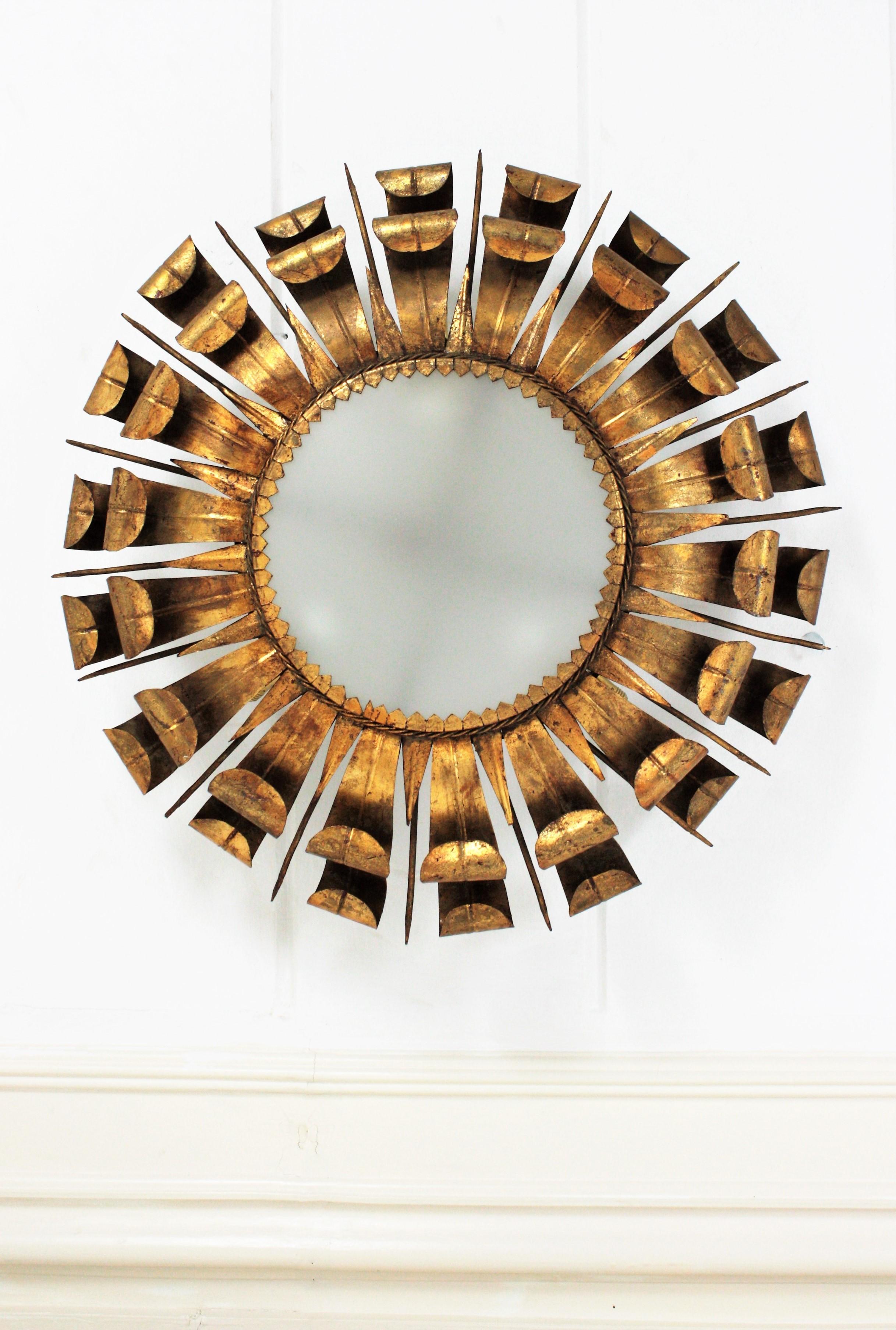 A gorgeous double layered eyelash sunburst ceiling flush mount or pendant with nail accents, France, 1950s.
The frame is made by a double layer of wrought iron curved beams with scrolled ending accented by pointed iron spikes. It has gold leaf