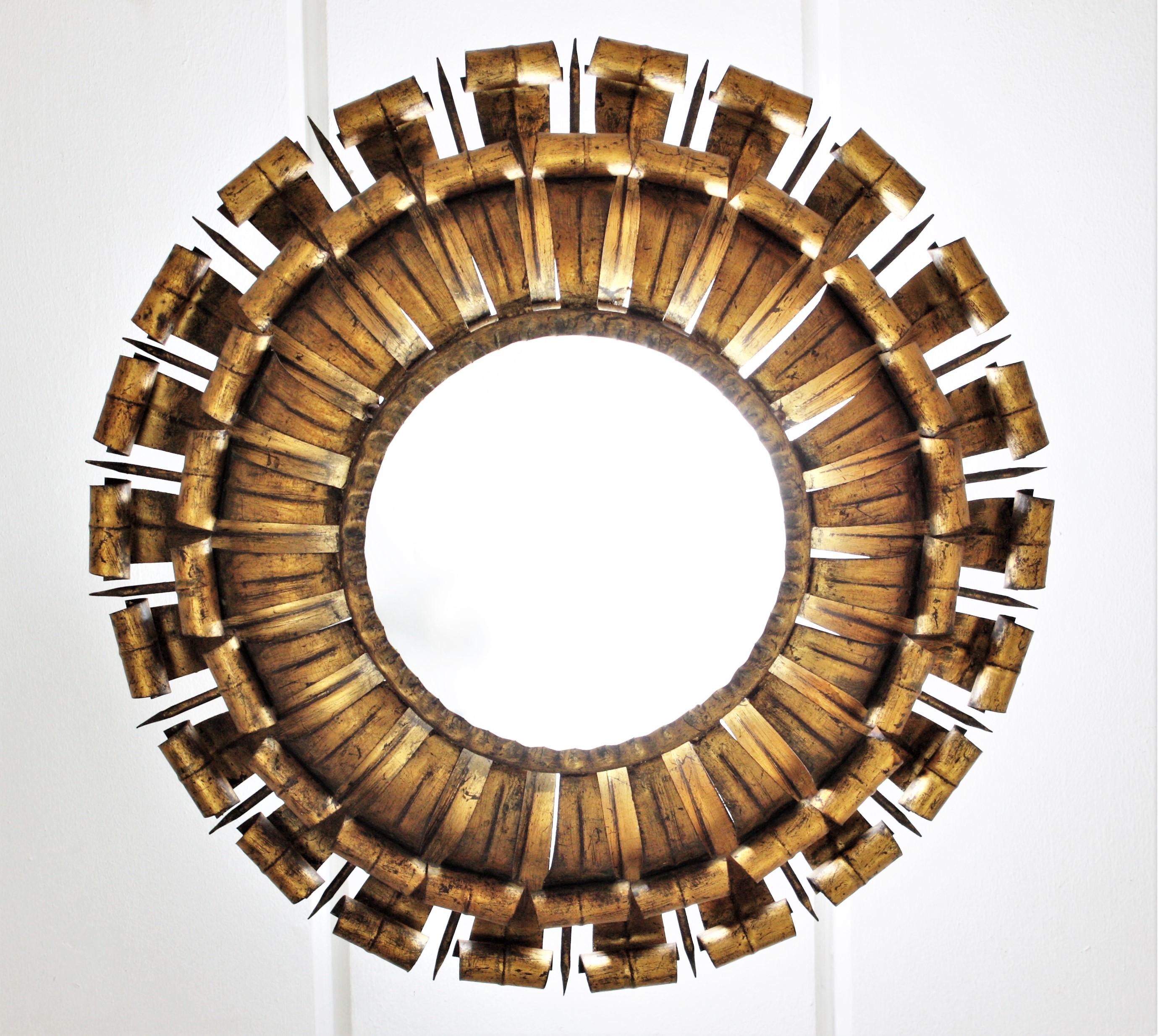 A gorgeous double layered eyelash sunburst ceiling flush mount / wall sconce with nail accents, France, 1950s.
The frame is made by a double layer of wrought iron curved beams with scrolled ending accented by pointed iron spikes. It has gold leaf