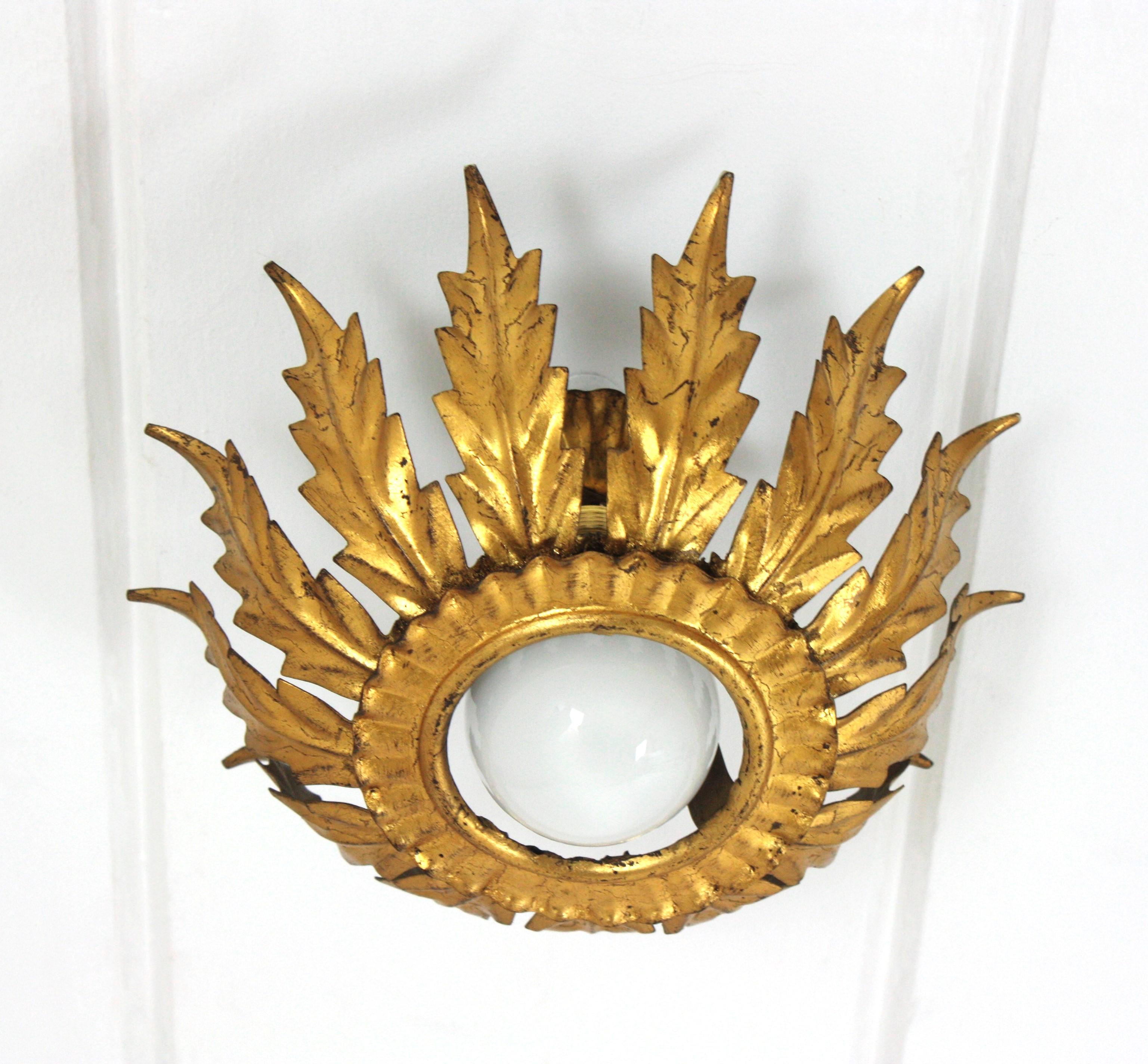 Eye-catching sunburst foliage flower flush mount light fixture in gold leaf gilt iron. France, 1940s.
This handwrought iron ceiling light fixture has a nice patina showing its original gold leaf gilding.
It can be used as a flush mount, as a wall