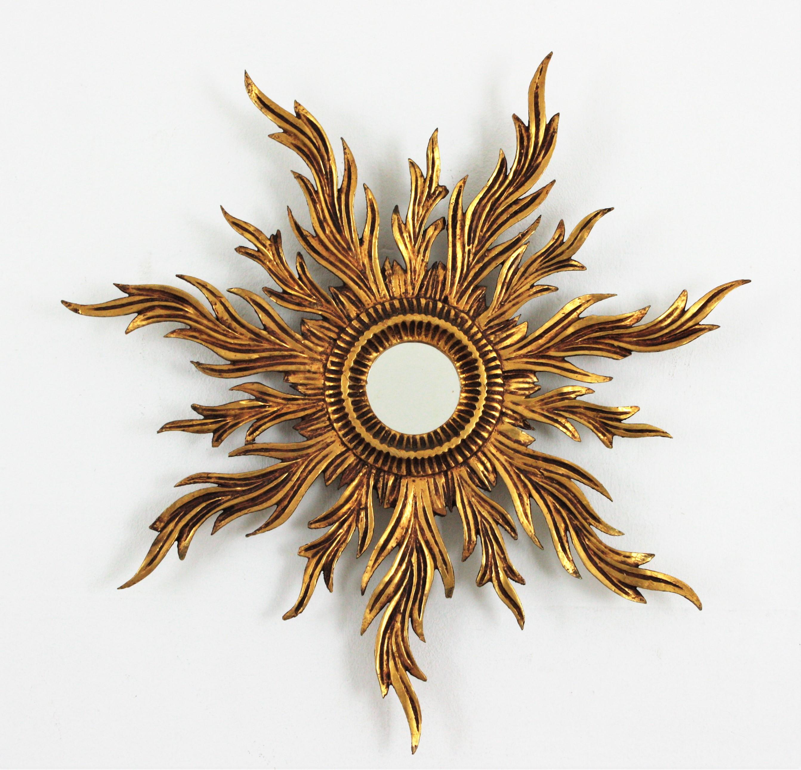 Finely carved gold leaf gilded sunburst mirror, France, 1920s.
Elegant sunburst mirror with a frame comprised by full of movement carved rays in two sizes. Finished in gold leaf gilding. This piece has a dramatic aged patina.
Place it alone or as