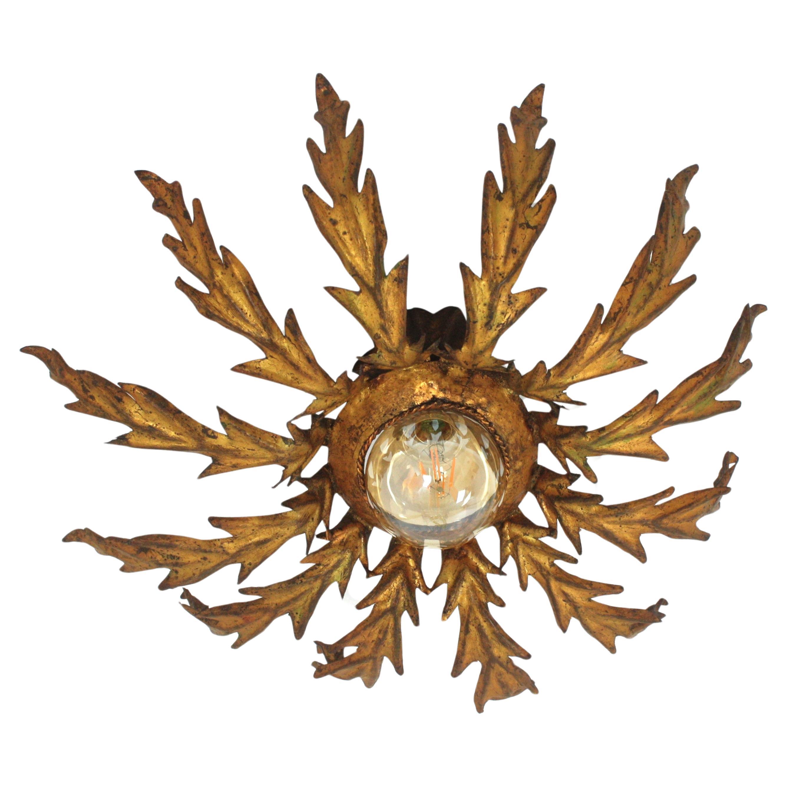 Sunburst Flower Foliage Flush mount in Gilt Iron. France, 1940s.
Eye-catching iron leafed sunburst light fixture with a layer of hand cut iron leaves surrounding a central light. It has a terrific patina with gold leaf gilding.
It has a design