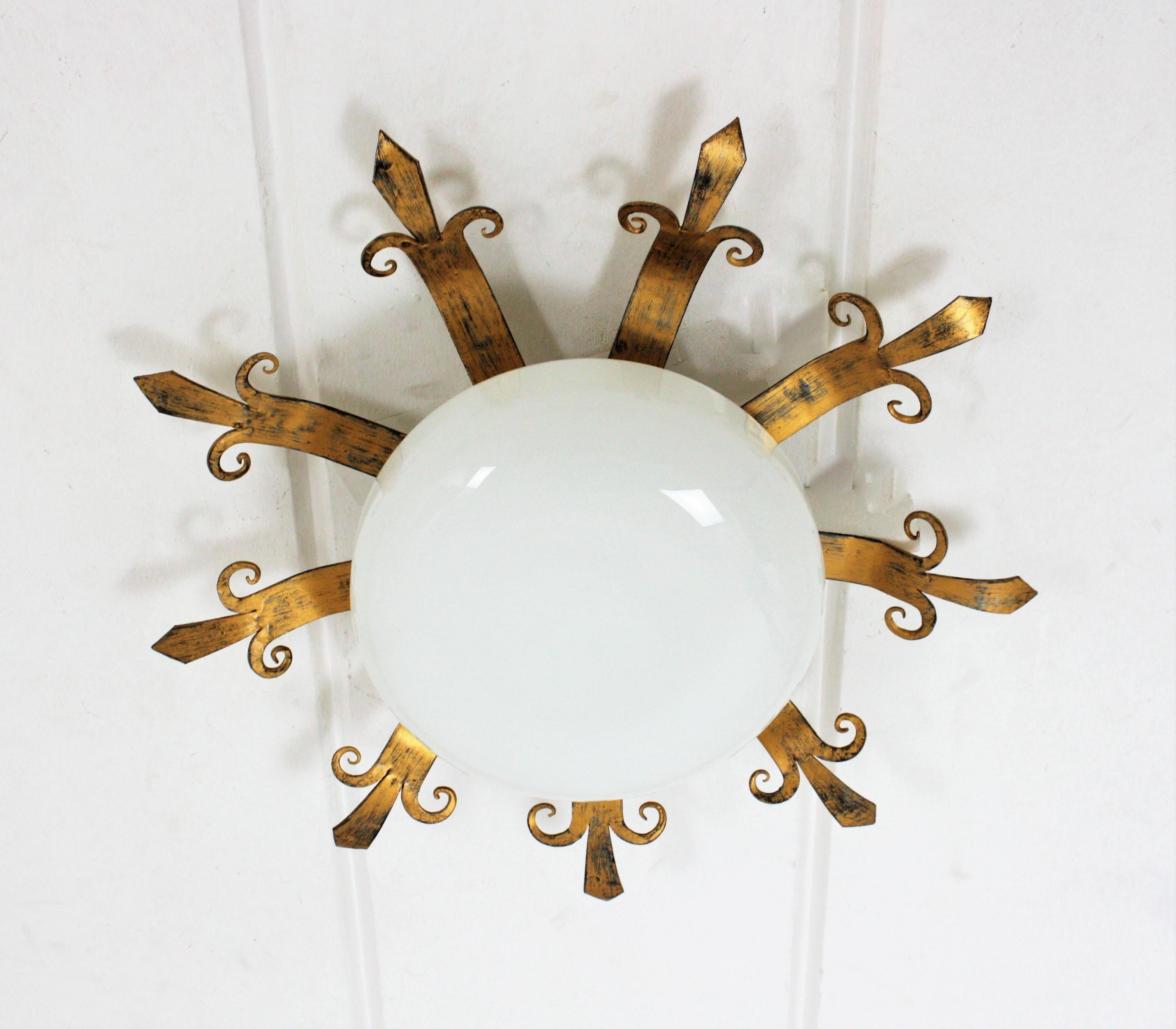 Eye-catching French sunburst flush mount in gilt metal and milk glass, 1950s
This Mid-Century sunburst starburst light fixture features a patinated gilt metal structure with a semi-spherical opaline glass shade.
It has a beautiful design with rays