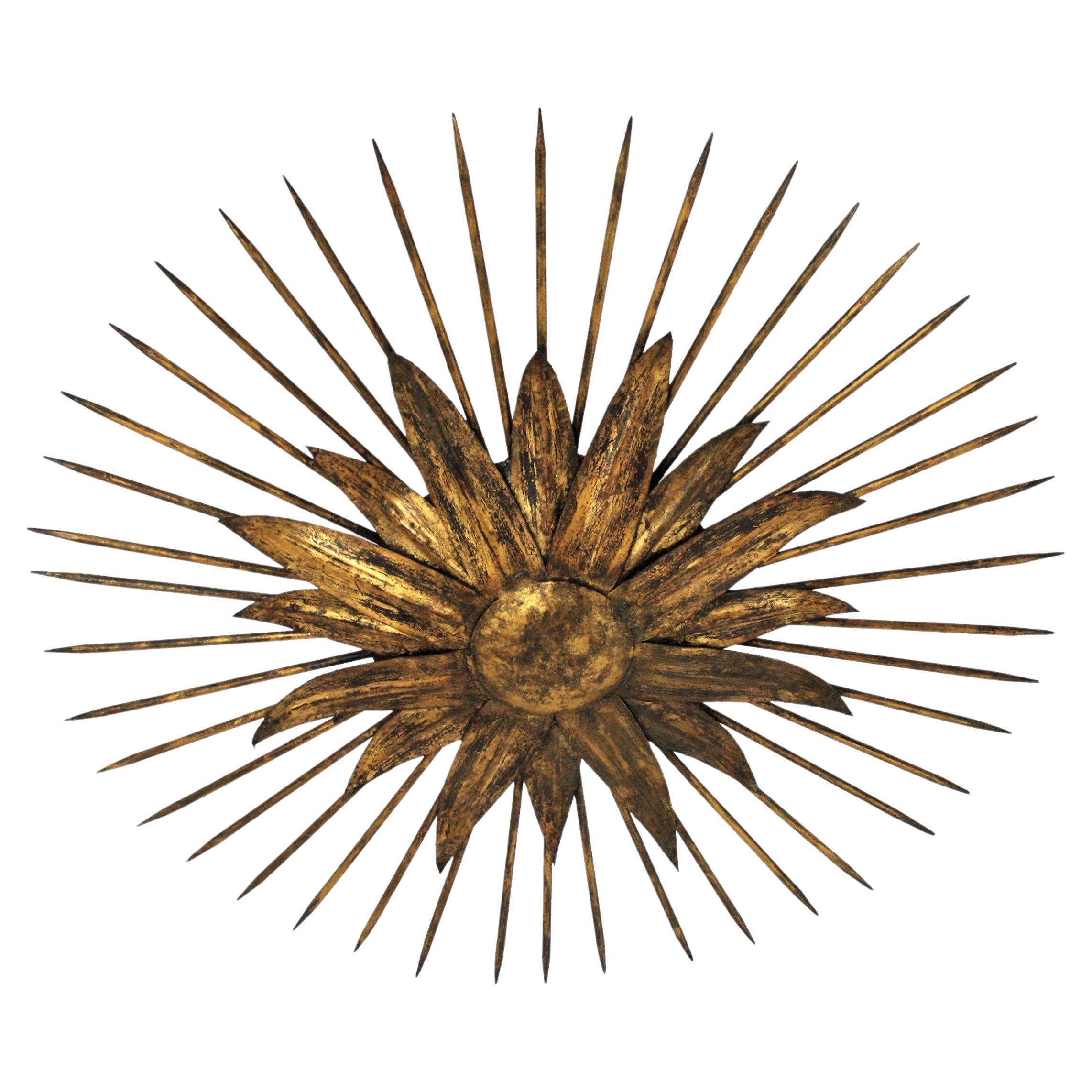 French modern neoclassical spikey sunburst flush mount / wall light in gilt iron with nail rays. France, 1940s.
Outstanding hand-hammered gold leaf gilt iron leafed sunburst light fixture from the late Art Deco period.
Highly decorative design with